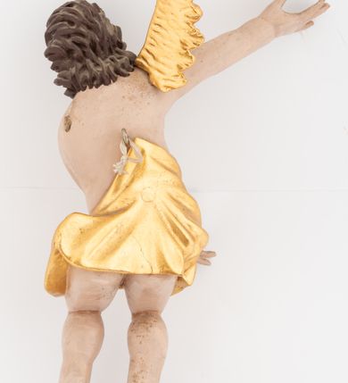 Zdjęcie nr 4: Dwie pełnoplastyczne rzeźby siedzących aniołów, ukazanych frontalnie, pochylonych w bok, z obiema rękami wyciągniętymi w bok. Twarze mają wydłużone, o pełnych policzkach, migdałowatych, dużych oczach, prostych nosach i wąskich ustach, okolone kręconymi włosami, opadającymi na tył głowy. W partii bioder przewiązane złoconą tkaniną. Ciała mają pulchne, o nieproporcjonalnych względem korpusu kończynach. Ich skrzydła są złocone, małe i rozłożone na boki. Polichromia ciała naturalistyczna.
