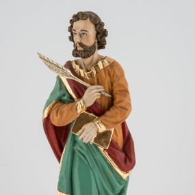 Zdjęcie nr 1: Rzeźba pełna, postać umieszczona na cokole przedstawiająca św. Marka Ewangelistę. Święty ukazany jest w pozycji stojącej, frontalnie, w kontrapoście, z prawą nogą zgiętą w kolanie i głową skierowaną na wprost. Prawą rękę przyciska do piersi, trzymając pióro, lewą przytrzymuje zamkniętą księgę. Święty ma pociągłą twarz o szeroko otwartych, niebieskich oczach, długim nosie i małych ustach, okoloną zwiniętymi w pukle włosami zakrywającymi uszy i formującymi lok nad czołem oraz wąsy i krótką brodę. Ubrany jest w jasnobrązową suknię lamowaną przy krawędziach złotem oraz w zielony, podbity czerwienią i lamowany złotem płaszcz przechodzący przez prawy bark i otaczający lewe biodro, układający się w głębokie fałdy. Stopy bose. Przy lewej nodze świętego widoczny fragment niewielkiej postaci lwa. Polichromia w partiach ciała naturalistyczna. 