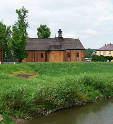 Zdjęcie nr 2: Kościół drewniany o konstrukcji zrębowej, na betonowym podmurowaniu przesłoniętym daszkiem gontowym. Elewacje jednolite, szalowane z listwowaniem, wzmocnione lisicami. Więźba dachowa drewniana, krokwiowa, o systemie więźbowo-zaskrzynieniowym. Kościół orientowany, jednonawowy, nawa na rzucie wydłużonego prostokąta, prezbiterium nieco węższe, zakończone trójbocznie. Do północnej ściany prezbiterium i nawy przylega zakrystia połączona z aneksem na rzucie prostokąta, do nawy od południa przylega duża kaplica na planie prostokąta otwarta do nawy otworem o wykroju prostokąta zamkniętego łukiem odcinkowym. 
Ściany wnętrza podzielone trzema parami pilastrów. Pomiędzy nawą a prezbiterium arkadowy otwór tęczowy z prostą belką. Parapet chóru muzycznego w zachodniej części nawy, oparty na dwóch kolumnach o wielobocznych trzonach. Wnętrze nakryte stropem płaskim, w nawie z zaskrzynieniami podtrzymywanymi przez trzy pary słupów o wielobocznych i kręconych trzonach. Otwory drzwiowe o prostokątnym wykroju zamknięte drzwiami jednoskrzydłowymi w północnej ścianie nawy oraz prezbiterium. Posadzka z płyt kamiennych. 
Elewacja frontowa jednoosiowa, zamknięta trójkątnym szczytem rozszerzającym się ku dołowi. Na osi ganek oparty na czterech słupach, nakryty dwuspadowym daszkiem gontowym, wejście do kościoła z dwuskrzydłowymi drzwiami. W partii szczytu dwa okna w formie stojącego prostokąta zamkniętego łukiem półkolistym. W elewacji południowej cztery otwory okienne w formie stojącego prostokąta zamkniętego łukiem półkolistym, dwa w nawie i dwa w prezbiterium oraz dwa analogiczne okna na zachodniej i wschodniej ścianie kaplicy. Elewacja północna z dwoma otworami okiennymi w formie stojącego prostokąta zamkniętego łukiem półkolistym, trzema oknami i wejściem do zakrystii i aneksu. Kościół nakryty wspólnym dachem o jednej kalenicy nad prezbiterium i nawą, gontowym, dwuspadowym, z przedłużoną połacią przekrywającą zaskrzynienia. W jednej trzeciej długości dachu nad nawą od strony prezbiterium wznosi się ponad kalenicą wieżyczka na sygnaturkę, na ośmiobocznym obitym blachą trzonie, z latarnią zwieńczoną niewielkim cebulastym hełmem. Kaplica boczna nakryta kopułą krytą gontem, z latarnią. Nad zakrystią i aneksem dach jednospadowy.
 
