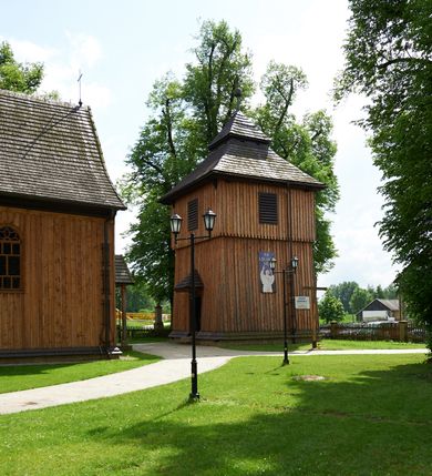 Zdjęcie nr 10: Kościół drewniany o konstrukcji zrębowej, na betonowym podmurowaniu przesłoniętym daszkiem gontowym. Elewacje jednolite, szalowane z listwowaniem, wzmocnione lisicami. Więźba dachowa drewniana, krokwiowa, o systemie więźbowo-zaskrzynieniowym. Kościół orientowany, jednonawowy, nawa na rzucie wydłużonego prostokąta, prezbiterium nieco węższe, zakończone trójbocznie. Do północnej ściany prezbiterium i nawy przylega zakrystia połączona z aneksem na rzucie prostokąta, do nawy od południa przylega duża kaplica na planie prostokąta otwarta do nawy otworem o wykroju prostokąta zamkniętego łukiem odcinkowym. 
Ściany wnętrza podzielone trzema parami pilastrów. Pomiędzy nawą a prezbiterium arkadowy otwór tęczowy z prostą belką. Parapet chóru muzycznego w zachodniej części nawy, oparty na dwóch kolumnach o wielobocznych trzonach. Wnętrze nakryte stropem płaskim, w nawie z zaskrzynieniami podtrzymywanymi przez trzy pary słupów o wielobocznych i kręconych trzonach. Otwory drzwiowe o prostokątnym wykroju zamknięte drzwiami jednoskrzydłowymi w północnej ścianie nawy oraz prezbiterium. Posadzka z płyt kamiennych. 
Elewacja frontowa jednoosiowa, zamknięta trójkątnym szczytem rozszerzającym się ku dołowi. Na osi ganek oparty na czterech słupach, nakryty dwuspadowym daszkiem gontowym, wejście do kościoła z dwuskrzydłowymi drzwiami. W partii szczytu dwa okna w formie stojącego prostokąta zamkniętego łukiem półkolistym. W elewacji południowej cztery otwory okienne w formie stojącego prostokąta zamkniętego łukiem półkolistym, dwa w nawie i dwa w prezbiterium oraz dwa analogiczne okna na zachodniej i wschodniej ścianie kaplicy. Elewacja północna z dwoma otworami okiennymi w formie stojącego prostokąta zamkniętego łukiem półkolistym, trzema oknami i wejściem do zakrystii i aneksu. Kościół nakryty wspólnym dachem o jednej kalenicy nad prezbiterium i nawą, gontowym, dwuspadowym, z przedłużoną połacią przekrywającą zaskrzynienia. W jednej trzeciej długości dachu nad nawą od strony prezbiterium wznosi się ponad kalenicą wieżyczka na sygnaturkę, na ośmiobocznym obitym blachą trzonie, z latarnią zwieńczoną niewielkim cebulastym hełmem. Kaplica boczna nakryta kopułą krytą gontem, z latarnią. Nad zakrystią i aneksem dach jednospadowy.
 
