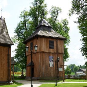 Zdjęcie nr 1: Dzwonnica drewniana, konstrukcji słupowej, ściany, szalowane z listwowaniem, więźba dachowa drewniana. Założona na planie kwadratu, na betonowym podmurowaniu, przesłoniętym okapowym daszkiem gontowym. Ściany zwężające się ku górze, z izbicą. Dach gontowy, czterospadowy, łamany, zakończony metalowym szpikulcem z kulą i krzyżem. Otwór drzwiowy w ścianie wschodniej o wykroju stojącego prostokąta zamknięty drzwiami jednoskrzydłowymi, nakryty trójspadowym daszkiem gontowym. Otwory głosowe w formie stojącego prostokąta, po jednym na każdej ścianie w partii izbicy. 