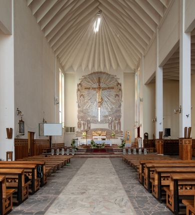 Zdjęcie nr 5: Świątynia trójnawowa, ośmioprzęsłowa o konstrukcji żelbetowej, tynkowana. Prezbiterium zamknięte prostą ścianą, umieszczone na kilkustopniowym podwyższeniu. Prostokątna zakrystia od strony wschodniej oraz prostokątna kaplica od strony zachodniej. Nawy, z których środkowa wyższa i szersza od bocznych wydzielone smukłymi filarami na rzucie prostokąta. Nakryte ekspresyjnym, żelbetowym stropem o rzeźbiarskiej formie. Chór muzyczny od strony południowej o konstrukcji żelbetowej z prostym parapetem zamkniętym od góry drewnianą poręczą. Fasada dwukondygnacyjna z umieszczonym w przyziemiu pięcioosiowym wejściem w formie prostokątnych otworów drzwiowych dostępnych wysokimi schodami. Otwory drzwiowe wydzielone żelbetowymi lizenami, podziały kontynuowane także w drugiej kondygnacji, gdzie w miejsce otworów drzwiowych wysokie, prostokątne okna. Elewacja zamknięta ścianą szczytową w kształcie trójkąta o nierównych bokach i zwieńczona prostym krzyżem. Od zachodu do elewacji dostawiona wieża dzwonna na rzucie trójkąta zwężającego się ku górze i nakryta strzelistym, ostrosłupowym hełmem zwieńczonym krzyżem. Elewacje boczne ośmioosiowe, artykułowane lizenami. W czterech pierwszych osiach od południa i na szerokości prezbiterium po dwa wysokie i prostokątne okna, w pozostałych pojedyncze okna i trójkątne szczyty. Od wschodu dach kryty blachą, dwuspadowy o nierównych połaciach; nad nawą boczną od strony wschodniej jednopołaciowy. Niewielka wieżyczka na sygnaturkę na kalenicy dachu od strony północnej.