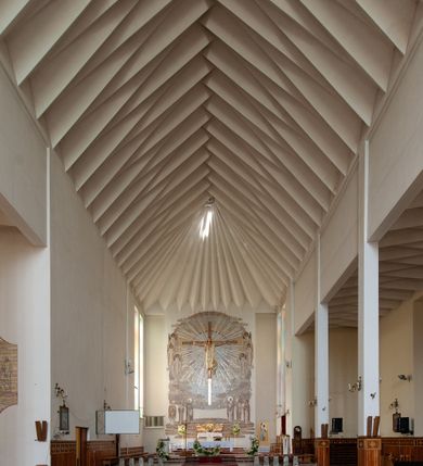 Zdjęcie nr 4: Świątynia trójnawowa, ośmioprzęsłowa o konstrukcji żelbetowej, tynkowana. Prezbiterium zamknięte prostą ścianą, umieszczone na kilkustopniowym podwyższeniu. Prostokątna zakrystia od strony wschodniej oraz prostokątna kaplica od strony zachodniej. Nawy, z których środkowa wyższa i szersza od bocznych wydzielone smukłymi filarami na rzucie prostokąta. Nakryte ekspresyjnym, żelbetowym stropem o rzeźbiarskiej formie. Chór muzyczny od strony południowej o konstrukcji żelbetowej z prostym parapetem zamkniętym od góry drewnianą poręczą. Fasada dwukondygnacyjna z umieszczonym w przyziemiu pięcioosiowym wejściem w formie prostokątnych otworów drzwiowych dostępnych wysokimi schodami. Otwory drzwiowe wydzielone żelbetowymi lizenami, podziały kontynuowane także w drugiej kondygnacji, gdzie w miejsce otworów drzwiowych wysokie, prostokątne okna. Elewacja zamknięta ścianą szczytową w kształcie trójkąta o nierównych bokach i zwieńczona prostym krzyżem. Od zachodu do elewacji dostawiona wieża dzwonna na rzucie trójkąta zwężającego się ku górze i nakryta strzelistym, ostrosłupowym hełmem zwieńczonym krzyżem. Elewacje boczne ośmioosiowe, artykułowane lizenami. W czterech pierwszych osiach od południa i na szerokości prezbiterium po dwa wysokie i prostokątne okna, w pozostałych pojedyncze okna i trójkątne szczyty. Od wschodu dach kryty blachą, dwuspadowy o nierównych połaciach; nad nawą boczną od strony wschodniej jednopołaciowy. Niewielka wieżyczka na sygnaturkę na kalenicy dachu od strony północnej.