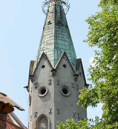 Zdjęcie nr 44: Kościół murowany z cegły i kamienia, tynkowany. Detal architektoniczny kamienny i rzeźbiony w tynku. Więźba dachowa drewniana, krokwiowa. Świątynia orientowana, jednonawowa, nawa na rzucie wydłużonego prostokąta, prezbiterium nieco węższe, zakończone wielobocznie, z wieżą na planie kwadratu. Do prezbiterium od północy przylega zakrystia z przedsionkiem i kruchtą na planie zbliżonym do prostokąta, do nawy od południa przybudowana kaplica na rzucie ośmioboku oraz od północy kruchta na planie kwadratu. Całość oszkarpowana. Wnętrze nakryte drewnianymi stropami i sufitami z wyprawą tynkową i polichromią. Pomiędzy nawą a prezbiterium półkolisty otwór tęczowy. Parapet chóru muzycznego w zachodniej części nawy, podparty na dwóch kolumnach. Otwory drzwiowe o wykroju prostokątnym, ostrołukowym i prostokątnym zamkniętym łukiem segmentowym. Drzwi drewniane obite listwami i płycinowe. Okna w formie stojącego prostokąta zamkniętego łukiem półkolistym, w wieży zamknięte łukiem ostrym, w metalowej oprawie, witrażowe. Posadzka z płyt ceramicznych. Elewacje opracowane jednolicie, tynkowane, zakończone gzymsem podokapowym, opięte dwuuskokowymi szkarpami. Elewacja zachodnia wieżowa, jednoosiowa, czterokondygnacyjna, z wydzielonym cokołem. Kondygnacje wydzielone gzymsami kordonowymi, ostatnia na planie ośmioboku. Na osi ostrołukowy portal z profilowanym obramieniem w tynku. Drzwi drewniane dwuskrzydłowe, obite listwami, z ostrołukowym naświetlem. Nad portalem owalna tablica fundacyjna z napisem „WIEŻA TA WYBUDOWANA / NA CZEŚĆ / MATKI BOSKIEJ / R(OKU) P(AŃSKIEGO) 1888”. Na froncie wieży, na osi, dwa ostrołukowe okna, na ścianach bocznych po trzy ostrołukowe okna, w najwyższej partii rząd okulusów. Wieża zakończona ośmioma trójkątnymi szczytami i ostrosłupowym hełmem z metalową koroną. Elewacje boczne przeprute oknami, po dwa w nawie i prezbiterium, alternowanymi szkarpami. W kaplicy i w zakrystii po dwa okna. Elewacja wschodnia pozbawiona okien. Kruchta północna przybudowana do korpusu, od frontu ujęta stylizowanymi półkolumnami dźwigającymi wklęsło-wypukły szczyt. W zewnętrzne ściany kościoła wmurowane współczesne, ceramiczne stacje drogi krzyżowej. Dachy dwuspadowe, kryte dachówką ceramiczną. Wyższy nad nawą, niższy nad prezbiterium. W połowie długości dachu, nad nawą, wieżyczka na sygnaturkę z latarnią, zwieńczona ostrosłupowym hełmem. Nad zakrystią ceramiczny dach pulpitowy, nad kruchtą dwuspadowy, nad kaplicą ostrosłupowy, kryty blachą. 