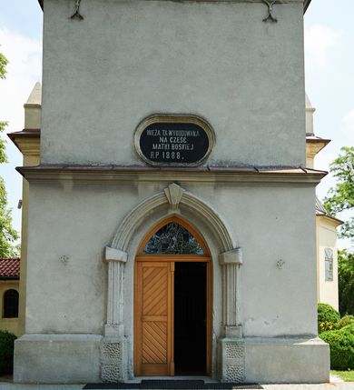 Zdjęcie nr 43: Kościół murowany z cegły i kamienia, tynkowany. Detal architektoniczny kamienny i rzeźbiony w tynku. Więźba dachowa drewniana, krokwiowa. Świątynia orientowana, jednonawowa, nawa na rzucie wydłużonego prostokąta, prezbiterium nieco węższe, zakończone wielobocznie, z wieżą na planie kwadratu. Do prezbiterium od północy przylega zakrystia z przedsionkiem i kruchtą na planie zbliżonym do prostokąta, do nawy od południa przybudowana kaplica na rzucie ośmioboku oraz od północy kruchta na planie kwadratu. Całość oszkarpowana. Wnętrze nakryte drewnianymi stropami i sufitami z wyprawą tynkową i polichromią. Pomiędzy nawą a prezbiterium półkolisty otwór tęczowy. Parapet chóru muzycznego w zachodniej części nawy, podparty na dwóch kolumnach. Otwory drzwiowe o wykroju prostokątnym, ostrołukowym i prostokątnym zamkniętym łukiem segmentowym. Drzwi drewniane obite listwami i płycinowe. Okna w formie stojącego prostokąta zamkniętego łukiem półkolistym, w wieży zamknięte łukiem ostrym, w metalowej oprawie, witrażowe. Posadzka z płyt ceramicznych. Elewacje opracowane jednolicie, tynkowane, zakończone gzymsem podokapowym, opięte dwuuskokowymi szkarpami. Elewacja zachodnia wieżowa, jednoosiowa, czterokondygnacyjna, z wydzielonym cokołem. Kondygnacje wydzielone gzymsami kordonowymi, ostatnia na planie ośmioboku. Na osi ostrołukowy portal z profilowanym obramieniem w tynku. Drzwi drewniane dwuskrzydłowe, obite listwami, z ostrołukowym naświetlem. Nad portalem owalna tablica fundacyjna z napisem „WIEŻA TA WYBUDOWANA / NA CZEŚĆ / MATKI BOSKIEJ / R(OKU) P(AŃSKIEGO) 1888”. Na froncie wieży, na osi, dwa ostrołukowe okna, na ścianach bocznych po trzy ostrołukowe okna, w najwyższej partii rząd okulusów. Wieża zakończona ośmioma trójkątnymi szczytami i ostrosłupowym hełmem z metalową koroną. Elewacje boczne przeprute oknami, po dwa w nawie i prezbiterium, alternowanymi szkarpami. W kaplicy i w zakrystii po dwa okna. Elewacja wschodnia pozbawiona okien. Kruchta północna przybudowana do korpusu, od frontu ujęta stylizowanymi półkolumnami dźwigającymi wklęsło-wypukły szczyt. W zewnętrzne ściany kościoła wmurowane współczesne, ceramiczne stacje drogi krzyżowej. Dachy dwuspadowe, kryte dachówką ceramiczną. Wyższy nad nawą, niższy nad prezbiterium. W połowie długości dachu, nad nawą, wieżyczka na sygnaturkę z latarnią, zwieńczona ostrosłupowym hełmem. Nad zakrystią ceramiczny dach pulpitowy, nad kruchtą dwuspadowy, nad kaplicą ostrosłupowy, kryty blachą. 