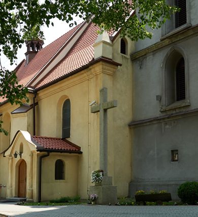 Zdjęcie nr 20: Kościół murowany z cegły i kamienia, tynkowany. Detal architektoniczny kamienny i rzeźbiony w tynku. Więźba dachowa drewniana, krokwiowa. Świątynia orientowana, jednonawowa, nawa na rzucie wydłużonego prostokąta, prezbiterium nieco węższe, zakończone wielobocznie, z wieżą na planie kwadratu. Do prezbiterium od północy przylega zakrystia z przedsionkiem i kruchtą na planie zbliżonym do prostokąta, do nawy od południa przybudowana kaplica na rzucie ośmioboku oraz od północy kruchta na planie kwadratu. Całość oszkarpowana. Wnętrze nakryte drewnianymi stropami i sufitami z wyprawą tynkową i polichromią. Pomiędzy nawą a prezbiterium półkolisty otwór tęczowy. Parapet chóru muzycznego w zachodniej części nawy, podparty na dwóch kolumnach. Otwory drzwiowe o wykroju prostokątnym, ostrołukowym i prostokątnym zamkniętym łukiem segmentowym. Drzwi drewniane obite listwami i płycinowe. Okna w formie stojącego prostokąta zamkniętego łukiem półkolistym, w wieży zamknięte łukiem ostrym, w metalowej oprawie, witrażowe. Posadzka z płyt ceramicznych. Elewacje opracowane jednolicie, tynkowane, zakończone gzymsem podokapowym, opięte dwuuskokowymi szkarpami. Elewacja zachodnia wieżowa, jednoosiowa, czterokondygnacyjna, z wydzielonym cokołem. Kondygnacje wydzielone gzymsami kordonowymi, ostatnia na planie ośmioboku. Na osi ostrołukowy portal z profilowanym obramieniem w tynku. Drzwi drewniane dwuskrzydłowe, obite listwami, z ostrołukowym naświetlem. Nad portalem owalna tablica fundacyjna z napisem „WIEŻA TA WYBUDOWANA / NA CZEŚĆ / MATKI BOSKIEJ / R(OKU) P(AŃSKIEGO) 1888”. Na froncie wieży, na osi, dwa ostrołukowe okna, na ścianach bocznych po trzy ostrołukowe okna, w najwyższej partii rząd okulusów. Wieża zakończona ośmioma trójkątnymi szczytami i ostrosłupowym hełmem z metalową koroną. Elewacje boczne przeprute oknami, po dwa w nawie i prezbiterium, alternowanymi szkarpami. W kaplicy i w zakrystii po dwa okna. Elewacja wschodnia pozbawiona okien. Kruchta północna przybudowana do korpusu, od frontu ujęta stylizowanymi półkolumnami dźwigającymi wklęsło-wypukły szczyt. W zewnętrzne ściany kościoła wmurowane współczesne, ceramiczne stacje drogi krzyżowej. Dachy dwuspadowe, kryte dachówką ceramiczną. Wyższy nad nawą, niższy nad prezbiterium. W połowie długości dachu, nad nawą, wieżyczka na sygnaturkę z latarnią, zwieńczona ostrosłupowym hełmem. Nad zakrystią ceramiczny dach pulpitowy, nad kruchtą dwuspadowy, nad kaplicą ostrosłupowy, kryty blachą. 