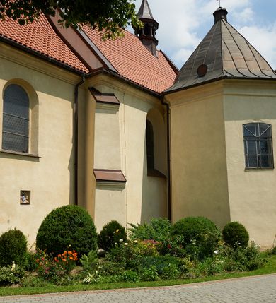 Zdjęcie nr 27: Kościół murowany z cegły i kamienia, tynkowany. Detal architektoniczny kamienny i rzeźbiony w tynku. Więźba dachowa drewniana, krokwiowa. Świątynia orientowana, jednonawowa, nawa na rzucie wydłużonego prostokąta, prezbiterium nieco węższe, zakończone wielobocznie, z wieżą na planie kwadratu. Do prezbiterium od północy przylega zakrystia z przedsionkiem i kruchtą na planie zbliżonym do prostokąta, do nawy od południa przybudowana kaplica na rzucie ośmioboku oraz od północy kruchta na planie kwadratu. Całość oszkarpowana. Wnętrze nakryte drewnianymi stropami i sufitami z wyprawą tynkową i polichromią. Pomiędzy nawą a prezbiterium półkolisty otwór tęczowy. Parapet chóru muzycznego w zachodniej części nawy, podparty na dwóch kolumnach. Otwory drzwiowe o wykroju prostokątnym, ostrołukowym i prostokątnym zamkniętym łukiem segmentowym. Drzwi drewniane obite listwami i płycinowe. Okna w formie stojącego prostokąta zamkniętego łukiem półkolistym, w wieży zamknięte łukiem ostrym, w metalowej oprawie, witrażowe. Posadzka z płyt ceramicznych. Elewacje opracowane jednolicie, tynkowane, zakończone gzymsem podokapowym, opięte dwuuskokowymi szkarpami. Elewacja zachodnia wieżowa, jednoosiowa, czterokondygnacyjna, z wydzielonym cokołem. Kondygnacje wydzielone gzymsami kordonowymi, ostatnia na planie ośmioboku. Na osi ostrołukowy portal z profilowanym obramieniem w tynku. Drzwi drewniane dwuskrzydłowe, obite listwami, z ostrołukowym naświetlem. Nad portalem owalna tablica fundacyjna z napisem „WIEŻA TA WYBUDOWANA / NA CZEŚĆ / MATKI BOSKIEJ / R(OKU) P(AŃSKIEGO) 1888”. Na froncie wieży, na osi, dwa ostrołukowe okna, na ścianach bocznych po trzy ostrołukowe okna, w najwyższej partii rząd okulusów. Wieża zakończona ośmioma trójkątnymi szczytami i ostrosłupowym hełmem z metalową koroną. Elewacje boczne przeprute oknami, po dwa w nawie i prezbiterium, alternowanymi szkarpami. W kaplicy i w zakrystii po dwa okna. Elewacja wschodnia pozbawiona okien. Kruchta północna przybudowana do korpusu, od frontu ujęta stylizowanymi półkolumnami dźwigającymi wklęsło-wypukły szczyt. W zewnętrzne ściany kościoła wmurowane współczesne, ceramiczne stacje drogi krzyżowej. Dachy dwuspadowe, kryte dachówką ceramiczną. Wyższy nad nawą, niższy nad prezbiterium. W połowie długości dachu, nad nawą, wieżyczka na sygnaturkę z latarnią, zwieńczona ostrosłupowym hełmem. Nad zakrystią ceramiczny dach pulpitowy, nad kruchtą dwuspadowy, nad kaplicą ostrosłupowy, kryty blachą. 