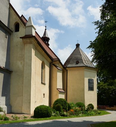 Zdjęcie nr 21: Kościół murowany z cegły i kamienia, tynkowany. Detal architektoniczny kamienny i rzeźbiony w tynku. Więźba dachowa drewniana, krokwiowa. Świątynia orientowana, jednonawowa, nawa na rzucie wydłużonego prostokąta, prezbiterium nieco węższe, zakończone wielobocznie, z wieżą na planie kwadratu. Do prezbiterium od północy przylega zakrystia z przedsionkiem i kruchtą na planie zbliżonym do prostokąta, do nawy od południa przybudowana kaplica na rzucie ośmioboku oraz od północy kruchta na planie kwadratu. Całość oszkarpowana. Wnętrze nakryte drewnianymi stropami i sufitami z wyprawą tynkową i polichromią. Pomiędzy nawą a prezbiterium półkolisty otwór tęczowy. Parapet chóru muzycznego w zachodniej części nawy, podparty na dwóch kolumnach. Otwory drzwiowe o wykroju prostokątnym, ostrołukowym i prostokątnym zamkniętym łukiem segmentowym. Drzwi drewniane obite listwami i płycinowe. Okna w formie stojącego prostokąta zamkniętego łukiem półkolistym, w wieży zamknięte łukiem ostrym, w metalowej oprawie, witrażowe. Posadzka z płyt ceramicznych. Elewacje opracowane jednolicie, tynkowane, zakończone gzymsem podokapowym, opięte dwuuskokowymi szkarpami. Elewacja zachodnia wieżowa, jednoosiowa, czterokondygnacyjna, z wydzielonym cokołem. Kondygnacje wydzielone gzymsami kordonowymi, ostatnia na planie ośmioboku. Na osi ostrołukowy portal z profilowanym obramieniem w tynku. Drzwi drewniane dwuskrzydłowe, obite listwami, z ostrołukowym naświetlem. Nad portalem owalna tablica fundacyjna z napisem „WIEŻA TA WYBUDOWANA / NA CZEŚĆ / MATKI BOSKIEJ / R(OKU) P(AŃSKIEGO) 1888”. Na froncie wieży, na osi, dwa ostrołukowe okna, na ścianach bocznych po trzy ostrołukowe okna, w najwyższej partii rząd okulusów. Wieża zakończona ośmioma trójkątnymi szczytami i ostrosłupowym hełmem z metalową koroną. Elewacje boczne przeprute oknami, po dwa w nawie i prezbiterium, alternowanymi szkarpami. W kaplicy i w zakrystii po dwa okna. Elewacja wschodnia pozbawiona okien. Kruchta północna przybudowana do korpusu, od frontu ujęta stylizowanymi półkolumnami dźwigającymi wklęsło-wypukły szczyt. W zewnętrzne ściany kościoła wmurowane współczesne, ceramiczne stacje drogi krzyżowej. Dachy dwuspadowe, kryte dachówką ceramiczną. Wyższy nad nawą, niższy nad prezbiterium. W połowie długości dachu, nad nawą, wieżyczka na sygnaturkę z latarnią, zwieńczona ostrosłupowym hełmem. Nad zakrystią ceramiczny dach pulpitowy, nad kruchtą dwuspadowy, nad kaplicą ostrosłupowy, kryty blachą. 