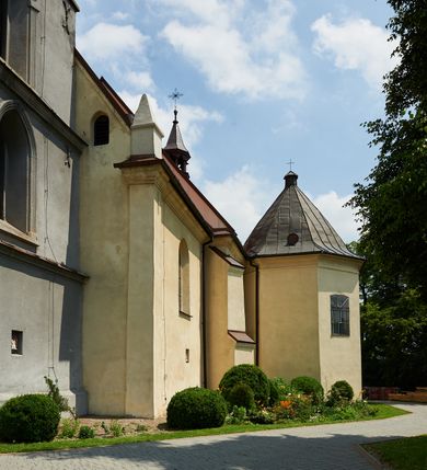 Zdjęcie nr 19: Kościół murowany z cegły i kamienia, tynkowany. Detal architektoniczny kamienny i rzeźbiony w tynku. Więźba dachowa drewniana, krokwiowa. Świątynia orientowana, jednonawowa, nawa na rzucie wydłużonego prostokąta, prezbiterium nieco węższe, zakończone wielobocznie, z wieżą na planie kwadratu. Do prezbiterium od północy przylega zakrystia z przedsionkiem i kruchtą na planie zbliżonym do prostokąta, do nawy od południa przybudowana kaplica na rzucie ośmioboku oraz od północy kruchta na planie kwadratu. Całość oszkarpowana. Wnętrze nakryte drewnianymi stropami i sufitami z wyprawą tynkową i polichromią. Pomiędzy nawą a prezbiterium półkolisty otwór tęczowy. Parapet chóru muzycznego w zachodniej części nawy, podparty na dwóch kolumnach. Otwory drzwiowe o wykroju prostokątnym, ostrołukowym i prostokątnym zamkniętym łukiem segmentowym. Drzwi drewniane obite listwami i płycinowe. Okna w formie stojącego prostokąta zamkniętego łukiem półkolistym, w wieży zamknięte łukiem ostrym, w metalowej oprawie, witrażowe. Posadzka z płyt ceramicznych. Elewacje opracowane jednolicie, tynkowane, zakończone gzymsem podokapowym, opięte dwuuskokowymi szkarpami. Elewacja zachodnia wieżowa, jednoosiowa, czterokondygnacyjna, z wydzielonym cokołem. Kondygnacje wydzielone gzymsami kordonowymi, ostatnia na planie ośmioboku. Na osi ostrołukowy portal z profilowanym obramieniem w tynku. Drzwi drewniane dwuskrzydłowe, obite listwami, z ostrołukowym naświetlem. Nad portalem owalna tablica fundacyjna z napisem „WIEŻA TA WYBUDOWANA / NA CZEŚĆ / MATKI BOSKIEJ / R(OKU) P(AŃSKIEGO) 1888”. Na froncie wieży, na osi, dwa ostrołukowe okna, na ścianach bocznych po trzy ostrołukowe okna, w najwyższej partii rząd okulusów. Wieża zakończona ośmioma trójkątnymi szczytami i ostrosłupowym hełmem z metalową koroną. Elewacje boczne przeprute oknami, po dwa w nawie i prezbiterium, alternowanymi szkarpami. W kaplicy i w zakrystii po dwa okna. Elewacja wschodnia pozbawiona okien. Kruchta północna przybudowana do korpusu, od frontu ujęta stylizowanymi półkolumnami dźwigającymi wklęsło-wypukły szczyt. W zewnętrzne ściany kościoła wmurowane współczesne, ceramiczne stacje drogi krzyżowej. Dachy dwuspadowe, kryte dachówką ceramiczną. Wyższy nad nawą, niższy nad prezbiterium. W połowie długości dachu, nad nawą, wieżyczka na sygnaturkę z latarnią, zwieńczona ostrosłupowym hełmem. Nad zakrystią ceramiczny dach pulpitowy, nad kruchtą dwuspadowy, nad kaplicą ostrosłupowy, kryty blachą. 