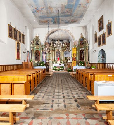 Zdjęcie nr 6: Kościół murowany z cegły i kamienia, tynkowany. Detal architektoniczny kamienny i rzeźbiony w tynku. Więźba dachowa drewniana, krokwiowa. Świątynia orientowana, jednonawowa, nawa na rzucie wydłużonego prostokąta, prezbiterium nieco węższe, zakończone wielobocznie, z wieżą na planie kwadratu. Do prezbiterium od północy przylega zakrystia z przedsionkiem i kruchtą na planie zbliżonym do prostokąta, do nawy od południa przybudowana kaplica na rzucie ośmioboku oraz od północy kruchta na planie kwadratu. Całość oszkarpowana. Wnętrze nakryte drewnianymi stropami i sufitami z wyprawą tynkową i polichromią. Pomiędzy nawą a prezbiterium półkolisty otwór tęczowy. Parapet chóru muzycznego w zachodniej części nawy, podparty na dwóch kolumnach. Otwory drzwiowe o wykroju prostokątnym, ostrołukowym i prostokątnym zamkniętym łukiem segmentowym. Drzwi drewniane obite listwami i płycinowe. Okna w formie stojącego prostokąta zamkniętego łukiem półkolistym, w wieży zamknięte łukiem ostrym, w metalowej oprawie, witrażowe. Posadzka z płyt ceramicznych. Elewacje opracowane jednolicie, tynkowane, zakończone gzymsem podokapowym, opięte dwuuskokowymi szkarpami. Elewacja zachodnia wieżowa, jednoosiowa, czterokondygnacyjna, z wydzielonym cokołem. Kondygnacje wydzielone gzymsami kordonowymi, ostatnia na planie ośmioboku. Na osi ostrołukowy portal z profilowanym obramieniem w tynku. Drzwi drewniane dwuskrzydłowe, obite listwami, z ostrołukowym naświetlem. Nad portalem owalna tablica fundacyjna z napisem „WIEŻA TA WYBUDOWANA / NA CZEŚĆ / MATKI BOSKIEJ / R(OKU) P(AŃSKIEGO) 1888”. Na froncie wieży, na osi, dwa ostrołukowe okna, na ścianach bocznych po trzy ostrołukowe okna, w najwyższej partii rząd okulusów. Wieża zakończona ośmioma trójkątnymi szczytami i ostrosłupowym hełmem z metalową koroną. Elewacje boczne przeprute oknami, po dwa w nawie i prezbiterium, alternowanymi szkarpami. W kaplicy i w zakrystii po dwa okna. Elewacja wschodnia pozbawiona okien. Kruchta północna przybudowana do korpusu, od frontu ujęta stylizowanymi półkolumnami dźwigającymi wklęsło-wypukły szczyt. W zewnętrzne ściany kościoła wmurowane współczesne, ceramiczne stacje drogi krzyżowej. Dachy dwuspadowe, kryte dachówką ceramiczną. Wyższy nad nawą, niższy nad prezbiterium. W połowie długości dachu, nad nawą, wieżyczka na sygnaturkę z latarnią, zwieńczona ostrosłupowym hełmem. Nad zakrystią ceramiczny dach pulpitowy, nad kruchtą dwuspadowy, nad kaplicą ostrosłupowy, kryty blachą. 