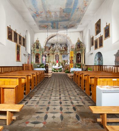 Zdjęcie nr 5: Kościół murowany z cegły i kamienia, tynkowany. Detal architektoniczny kamienny i rzeźbiony w tynku. Więźba dachowa drewniana, krokwiowa. Świątynia orientowana, jednonawowa, nawa na rzucie wydłużonego prostokąta, prezbiterium nieco węższe, zakończone wielobocznie, z wieżą na planie kwadratu. Do prezbiterium od północy przylega zakrystia z przedsionkiem i kruchtą na planie zbliżonym do prostokąta, do nawy od południa przybudowana kaplica na rzucie ośmioboku oraz od północy kruchta na planie kwadratu. Całość oszkarpowana. Wnętrze nakryte drewnianymi stropami i sufitami z wyprawą tynkową i polichromią. Pomiędzy nawą a prezbiterium półkolisty otwór tęczowy. Parapet chóru muzycznego w zachodniej części nawy, podparty na dwóch kolumnach. Otwory drzwiowe o wykroju prostokątnym, ostrołukowym i prostokątnym zamkniętym łukiem segmentowym. Drzwi drewniane obite listwami i płycinowe. Okna w formie stojącego prostokąta zamkniętego łukiem półkolistym, w wieży zamknięte łukiem ostrym, w metalowej oprawie, witrażowe. Posadzka z płyt ceramicznych. Elewacje opracowane jednolicie, tynkowane, zakończone gzymsem podokapowym, opięte dwuuskokowymi szkarpami. Elewacja zachodnia wieżowa, jednoosiowa, czterokondygnacyjna, z wydzielonym cokołem. Kondygnacje wydzielone gzymsami kordonowymi, ostatnia na planie ośmioboku. Na osi ostrołukowy portal z profilowanym obramieniem w tynku. Drzwi drewniane dwuskrzydłowe, obite listwami, z ostrołukowym naświetlem. Nad portalem owalna tablica fundacyjna z napisem „WIEŻA TA WYBUDOWANA / NA CZEŚĆ / MATKI BOSKIEJ / R(OKU) P(AŃSKIEGO) 1888”. Na froncie wieży, na osi, dwa ostrołukowe okna, na ścianach bocznych po trzy ostrołukowe okna, w najwyższej partii rząd okulusów. Wieża zakończona ośmioma trójkątnymi szczytami i ostrosłupowym hełmem z metalową koroną. Elewacje boczne przeprute oknami, po dwa w nawie i prezbiterium, alternowanymi szkarpami. W kaplicy i w zakrystii po dwa okna. Elewacja wschodnia pozbawiona okien. Kruchta północna przybudowana do korpusu, od frontu ujęta stylizowanymi półkolumnami dźwigającymi wklęsło-wypukły szczyt. W zewnętrzne ściany kościoła wmurowane współczesne, ceramiczne stacje drogi krzyżowej. Dachy dwuspadowe, kryte dachówką ceramiczną. Wyższy nad nawą, niższy nad prezbiterium. W połowie długości dachu, nad nawą, wieżyczka na sygnaturkę z latarnią, zwieńczona ostrosłupowym hełmem. Nad zakrystią ceramiczny dach pulpitowy, nad kruchtą dwuspadowy, nad kaplicą ostrosłupowy, kryty blachą. 