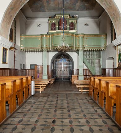 Zdjęcie nr 15: Kościół murowany z cegły i kamienia, tynkowany. Detal architektoniczny kamienny i rzeźbiony w tynku. Więźba dachowa drewniana, krokwiowa. Świątynia orientowana, jednonawowa, nawa na rzucie wydłużonego prostokąta, prezbiterium nieco węższe, zakończone wielobocznie, z wieżą na planie kwadratu. Do prezbiterium od północy przylega zakrystia z przedsionkiem i kruchtą na planie zbliżonym do prostokąta, do nawy od południa przybudowana kaplica na rzucie ośmioboku oraz od północy kruchta na planie kwadratu. Całość oszkarpowana. Wnętrze nakryte drewnianymi stropami i sufitami z wyprawą tynkową i polichromią. Pomiędzy nawą a prezbiterium półkolisty otwór tęczowy. Parapet chóru muzycznego w zachodniej części nawy, podparty na dwóch kolumnach. Otwory drzwiowe o wykroju prostokątnym, ostrołukowym i prostokątnym zamkniętym łukiem segmentowym. Drzwi drewniane obite listwami i płycinowe. Okna w formie stojącego prostokąta zamkniętego łukiem półkolistym, w wieży zamknięte łukiem ostrym, w metalowej oprawie, witrażowe. Posadzka z płyt ceramicznych. Elewacje opracowane jednolicie, tynkowane, zakończone gzymsem podokapowym, opięte dwuuskokowymi szkarpami. Elewacja zachodnia wieżowa, jednoosiowa, czterokondygnacyjna, z wydzielonym cokołem. Kondygnacje wydzielone gzymsami kordonowymi, ostatnia na planie ośmioboku. Na osi ostrołukowy portal z profilowanym obramieniem w tynku. Drzwi drewniane dwuskrzydłowe, obite listwami, z ostrołukowym naświetlem. Nad portalem owalna tablica fundacyjna z napisem „WIEŻA TA WYBUDOWANA / NA CZEŚĆ / MATKI BOSKIEJ / R(OKU) P(AŃSKIEGO) 1888”. Na froncie wieży, na osi, dwa ostrołukowe okna, na ścianach bocznych po trzy ostrołukowe okna, w najwyższej partii rząd okulusów. Wieża zakończona ośmioma trójkątnymi szczytami i ostrosłupowym hełmem z metalową koroną. Elewacje boczne przeprute oknami, po dwa w nawie i prezbiterium, alternowanymi szkarpami. W kaplicy i w zakrystii po dwa okna. Elewacja wschodnia pozbawiona okien. Kruchta północna przybudowana do korpusu, od frontu ujęta stylizowanymi półkolumnami dźwigającymi wklęsło-wypukły szczyt. W zewnętrzne ściany kościoła wmurowane współczesne, ceramiczne stacje drogi krzyżowej. Dachy dwuspadowe, kryte dachówką ceramiczną. Wyższy nad nawą, niższy nad prezbiterium. W połowie długości dachu, nad nawą, wieżyczka na sygnaturkę z latarnią, zwieńczona ostrosłupowym hełmem. Nad zakrystią ceramiczny dach pulpitowy, nad kruchtą dwuspadowy, nad kaplicą ostrosłupowy, kryty blachą. 