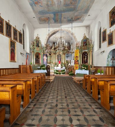 Zdjęcie nr 10: Kościół murowany z cegły i kamienia, tynkowany. Detal architektoniczny kamienny i rzeźbiony w tynku. Więźba dachowa drewniana, krokwiowa. Świątynia orientowana, jednonawowa, nawa na rzucie wydłużonego prostokąta, prezbiterium nieco węższe, zakończone wielobocznie, z wieżą na planie kwadratu. Do prezbiterium od północy przylega zakrystia z przedsionkiem i kruchtą na planie zbliżonym do prostokąta, do nawy od południa przybudowana kaplica na rzucie ośmioboku oraz od północy kruchta na planie kwadratu. Całość oszkarpowana. Wnętrze nakryte drewnianymi stropami i sufitami z wyprawą tynkową i polichromią. Pomiędzy nawą a prezbiterium półkolisty otwór tęczowy. Parapet chóru muzycznego w zachodniej części nawy, podparty na dwóch kolumnach. Otwory drzwiowe o wykroju prostokątnym, ostrołukowym i prostokątnym zamkniętym łukiem segmentowym. Drzwi drewniane obite listwami i płycinowe. Okna w formie stojącego prostokąta zamkniętego łukiem półkolistym, w wieży zamknięte łukiem ostrym, w metalowej oprawie, witrażowe. Posadzka z płyt ceramicznych. Elewacje opracowane jednolicie, tynkowane, zakończone gzymsem podokapowym, opięte dwuuskokowymi szkarpami. Elewacja zachodnia wieżowa, jednoosiowa, czterokondygnacyjna, z wydzielonym cokołem. Kondygnacje wydzielone gzymsami kordonowymi, ostatnia na planie ośmioboku. Na osi ostrołukowy portal z profilowanym obramieniem w tynku. Drzwi drewniane dwuskrzydłowe, obite listwami, z ostrołukowym naświetlem. Nad portalem owalna tablica fundacyjna z napisem „WIEŻA TA WYBUDOWANA / NA CZEŚĆ / MATKI BOSKIEJ / R(OKU) P(AŃSKIEGO) 1888”. Na froncie wieży, na osi, dwa ostrołukowe okna, na ścianach bocznych po trzy ostrołukowe okna, w najwyższej partii rząd okulusów. Wieża zakończona ośmioma trójkątnymi szczytami i ostrosłupowym hełmem z metalową koroną. Elewacje boczne przeprute oknami, po dwa w nawie i prezbiterium, alternowanymi szkarpami. W kaplicy i w zakrystii po dwa okna. Elewacja wschodnia pozbawiona okien. Kruchta północna przybudowana do korpusu, od frontu ujęta stylizowanymi półkolumnami dźwigającymi wklęsło-wypukły szczyt. W zewnętrzne ściany kościoła wmurowane współczesne, ceramiczne stacje drogi krzyżowej. Dachy dwuspadowe, kryte dachówką ceramiczną. Wyższy nad nawą, niższy nad prezbiterium. W połowie długości dachu, nad nawą, wieżyczka na sygnaturkę z latarnią, zwieńczona ostrosłupowym hełmem. Nad zakrystią ceramiczny dach pulpitowy, nad kruchtą dwuspadowy, nad kaplicą ostrosłupowy, kryty blachą. 