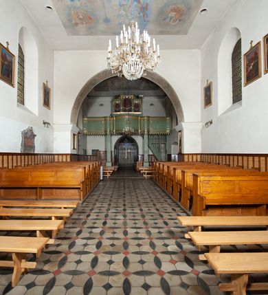 Zdjęcie nr 12: Kościół murowany z cegły i kamienia, tynkowany. Detal architektoniczny kamienny i rzeźbiony w tynku. Więźba dachowa drewniana, krokwiowa. Świątynia orientowana, jednonawowa, nawa na rzucie wydłużonego prostokąta, prezbiterium nieco węższe, zakończone wielobocznie, z wieżą na planie kwadratu. Do prezbiterium od północy przylega zakrystia z przedsionkiem i kruchtą na planie zbliżonym do prostokąta, do nawy od południa przybudowana kaplica na rzucie ośmioboku oraz od północy kruchta na planie kwadratu. Całość oszkarpowana. Wnętrze nakryte drewnianymi stropami i sufitami z wyprawą tynkową i polichromią. Pomiędzy nawą a prezbiterium półkolisty otwór tęczowy. Parapet chóru muzycznego w zachodniej części nawy, podparty na dwóch kolumnach. Otwory drzwiowe o wykroju prostokątnym, ostrołukowym i prostokątnym zamkniętym łukiem segmentowym. Drzwi drewniane obite listwami i płycinowe. Okna w formie stojącego prostokąta zamkniętego łukiem półkolistym, w wieży zamknięte łukiem ostrym, w metalowej oprawie, witrażowe. Posadzka z płyt ceramicznych. Elewacje opracowane jednolicie, tynkowane, zakończone gzymsem podokapowym, opięte dwuuskokowymi szkarpami. Elewacja zachodnia wieżowa, jednoosiowa, czterokondygnacyjna, z wydzielonym cokołem. Kondygnacje wydzielone gzymsami kordonowymi, ostatnia na planie ośmioboku. Na osi ostrołukowy portal z profilowanym obramieniem w tynku. Drzwi drewniane dwuskrzydłowe, obite listwami, z ostrołukowym naświetlem. Nad portalem owalna tablica fundacyjna z napisem „WIEŻA TA WYBUDOWANA / NA CZEŚĆ / MATKI BOSKIEJ / R(OKU) P(AŃSKIEGO) 1888”. Na froncie wieży, na osi, dwa ostrołukowe okna, na ścianach bocznych po trzy ostrołukowe okna, w najwyższej partii rząd okulusów. Wieża zakończona ośmioma trójkątnymi szczytami i ostrosłupowym hełmem z metalową koroną. Elewacje boczne przeprute oknami, po dwa w nawie i prezbiterium, alternowanymi szkarpami. W kaplicy i w zakrystii po dwa okna. Elewacja wschodnia pozbawiona okien. Kruchta północna przybudowana do korpusu, od frontu ujęta stylizowanymi półkolumnami dźwigającymi wklęsło-wypukły szczyt. W zewnętrzne ściany kościoła wmurowane współczesne, ceramiczne stacje drogi krzyżowej. Dachy dwuspadowe, kryte dachówką ceramiczną. Wyższy nad nawą, niższy nad prezbiterium. W połowie długości dachu, nad nawą, wieżyczka na sygnaturkę z latarnią, zwieńczona ostrosłupowym hełmem. Nad zakrystią ceramiczny dach pulpitowy, nad kruchtą dwuspadowy, nad kaplicą ostrosłupowy, kryty blachą. 