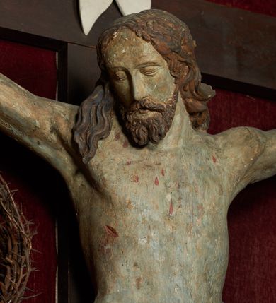 Zdjęcie nr 2: Rzeźba Chrystusa umarłego przybita do prostego krzyża trzema gwoździami. Ciało w lekkim zwisie o szeroko rozłożonych ramionach, układających się w delikatny łuk, głowa opadająca na prawy bark, nogi ugięte w kolanach, stopy skrzyżowane w układzie prawa na lewą. Chrystus ma pociągłą twarz, o migdałowatych, zamkniętych oczach, wąskim nosie i małych, rozchylonych ustach. Twarz okolona krótką, falowaną i rozdwajającą się w dwa pukle brodą oraz falowanymi włosami opadającymi na prawe ramię i kark. Ciało szczupłe, o delikatnym zarysowanym modelunku mięśni klatki piersiowej oraz ramion i nóg. Biodra przewiązane krótkim perizonium, zawiązanym na prawym boku. Ciało figury polichromowane naturalistycznie, włosy w kolorze brązowym, perizonium złocone. Na pionowej belce krzyża tabliczka z napisem „IN / RI”.

