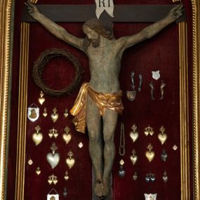 Zdjęcie nr 1: Rzeźba Chrystusa umarłego przybita do prostego krzyża trzema gwoździami. Ciało w lekkim zwisie o szeroko rozłożonych ramionach, układających się w delikatny łuk, głowa opadająca na prawy bark, nogi ugięte w kolanach, stopy skrzyżowane w układzie prawa na lewą. Chrystus ma pociągłą twarz, o migdałowatych, zamkniętych oczach, wąskim nosie i małych, rozchylonych ustach. Twarz okolona krótką, falowaną i rozdwajającą się w dwa pukle brodą oraz falowanymi włosami opadającymi na prawe ramię i kark. Ciało szczupłe, o delikatnym zarysowanym modelunku mięśni klatki piersiowej oraz ramion i nóg. Biodra przewiązane krótkim perizonium, zawiązanym na prawym boku. Ciało figury polichromowane naturalistycznie, włosy w kolorze brązowym, perizonium złocone. Na pionowej belce krzyża tabliczka z napisem „IN / RI”.

