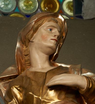 Zdjęcie nr 4: Rzeźba drążona z tyłu, ustawiona na niskiej podstawie. Figura zwrócona jest frontalnie, z głową skierowaną w lewo, w kontrapoście, o odchylonej i esowato wygiętej sylwetce. Twarz ma szczupłą, o migdałowatych, głęboko osadzonych oczach, prostym nosie, wąskich ustach, z uwypukloną brodą, okoloną jasnymi, falowanymi włosami ukrytymi pod welonem. Święta ubrana jest w przylegającą do ciała złoconą tunikę przepasaną w talii, na lewe ramię ma narzucony płaszcz, opadający po bokach postaci z fragmentem tkaniny zarzuconym na lewą nogę, na głowie ma welon, rozwiany na plecy. Ciało polichromowane naturalistycznie.
