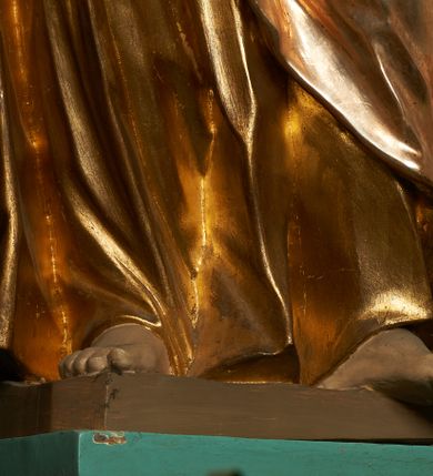 Zdjęcie nr 7: Rzeźba drążona z tyłu, ustawiona na niskiej podstawie. Figura zwrócona jest frontalnie, z uniesioną głową skierowaną w prawo, odchylona, w kontrapoście. W lewej odchylonej od ciała ręce trzyma włócznię, prawą podtrzymuje z przodu połę płaszcza. Twarz ma szczupłą, o głęboko osadzonych oczach skierowanych do góry, lekko garbatym nosie i wąskich rozchylonych ustach, okoloną gęstą, silnie skręconą w dwa grube pukle brodą. Włosy ma brązowe, krótkie, kręcone. Joachim ubrany jest w złoconą tunikę, przepasaną w talii oraz złocony płaszcz zarzucony na prawe ramię, otaczający postać, z połą tkaniny podtrzymywaną z przodu prawą ręką. Polichromia ciała naturalistyczna. 