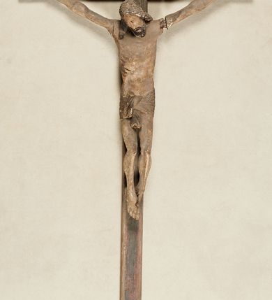 Zdjęcie nr 1: Figura umarłego Chrystusa przybita do krzyża trzema gwoździami. Ciało w lekkim zwisie, o ramionach układających się w delikatny łuk, nogi lekko ugięte, stopy skrzyżowane w układzie prawa na lewą. Chrystus ma wąską, pociągłą twarz, o zamkniętych oczach, prostym nosie i otwartych ustach. Twarz okolona krótką brodą oraz włosami sięgającymi ramion, rzeźbionymi w regularne fale. Ciało ma szczupłe i smukłe, o delikatnie zaznaczonych żebrach klatki piersiowej oraz ranie w boku. Perizonium w formie krótkiej, ściśle opinającej biodra tkaniny, zawiązanej w partii podbrzusza. Polichromia figury naturalistyczna, zachowana fragmentarycznie. 


