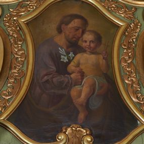 Zdjęcie nr 1: Obraz w formie zbliżonej do trapezu, o wklęsłych bokach, u spodu zamknięty faliście, u góry zaś wypukłą linią. W centrum obrazu przedstawienie św. Józefa w półpostaci, skierowanego w trzech czwartych w lewo, z pochyloną głową. Lewą ręką podtrzymuje Dzieciątko, prawą dłoń, w której trzyma gałązkę lilii kładzie na jego kolanie. Twarz ma pociągłą, o okrągłych, półprzymkniętych oczach, prostym, dużym nosie i pełnych ustach, okoloną jasnobrązową, krótką brodą i włosami. Ubrany jest w fioletową, obszerną tunikę oraz brązowy płaszcz, zarzucony na lewe ramię i otaczający postać. Dzieciątko w pozycji siedzącej, zwrócone w trzech czwartych w prawo, w lewej, uniesionej ręce trzyma krzyżyk, w prawej dłoni położonej na dłoni Józefa gałązkę lilii. Ma okrągłą twarz, o dużych, okrągłych oczach, małym nosie i pełnych ustach, okoloną krótkimi, jasnymi włosami. W partii bioder przepasane jest białą tkaniną. Postacie ukazane na jasnobrązowym tle. 
