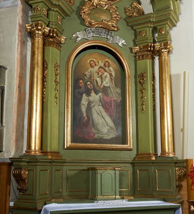 Zdjęcie nr 2: Nastawa ołtarzowa architektoniczna, jednoosiowa, jednokondygnacyjna ze zwieńczeniem, ustawiona na dwustrefowym cokole z dwoma prostopadłościanami wyodrębnionymi po bokach. Ołtarz sarkofagowy, od frontu zdobiony malowaną koroną cierniową z narzędziami Męki Pańskiej. Mensa drewniana, na niej ustawione tabernakulum w formie drewnianej skrzynki, ujętej z przodu pilastrami podtrzymującymi profilowany gzyms opasujący całość. Drzwiczki w formie stojącego prostokąta zamkniętego łukiem odcinkowym nadwieszonym, dekorowane płyciną. Obie strefy cokołu dekorowane są prostokątnymi płycinami, na zewnętrzych krawędziach górnej strefy konsole podtrzymujące wsporniki. Nastawa flankowana ustawionymi pod kątem na zewnątrz opilastrowanymi filarami, dekorowanymi rocaille'owymi zwisami, i stojącymi przed nimi kolumnami. Podpory dźwigają osobne imposty połączone gzymsami oraz fragmenty przerwanego, falistego przyczółka z siedzącymi puttami. W polu środkowym wnęka w formie stojącego prostokąta ujętego profilowaną ramą dekorowaną perełkowaniem, z nieco mniejszym obrazem Śmierci św. Zofii. W przestrzeni nad obrazem rokokowy kartusz z napisem „ALTARE / PRIVILEGIATUM / PRO DEFUNCTIS”, poniżej wstęga z napisem „JESTEŚ ZABITY I ODKUPI=/ ŁEŚ NAS BOGU PRZEZ KREW / TWOJĘ Ob. V 9.”. Zwieńczenie w formie zbliżonej do trapezu i wklęsłych bokach i wypukłej górnej podstawie, ujęte falistą wstęgą, po bokach przyjmującą formę spływów wolutowych z kwiatowymi zwisami, opadających na ornament utworzony z rocaille'u i kratki. Całość zakończona krzyżem na wolutowej, stylizowanej podstawie. W polu obraz w formie zbliżonej do stojącego prostokąta o wklęsłych bokach i wypukłej podstawie i zamknięciu, w profilowanej ramie, z obrazem św. Rozalii. Struktura polichromowana w kolorze seledynowym, ze złoconymi kolumnami, profilami i ornamentyka oraz srebrzoną wstęgą. 