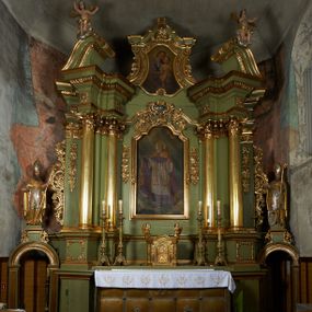 Zdjęcie nr 1: Nastawa ołtarzowa architektoniczna, jednoosiowa, jednokondygnacyjna ze zwieńczeniem, na cokole z czterema prostopadłościennymi postumentami wydzielonymi po bokach, z bramkami. Ołtarz drewniany, prostopadłościenny, z kamienną mensą z portatylem. Antependium drewniane obite miedzianą blachą, w formie leżącego prostokąta, ujętego profilowaną ramą, podzielone na dziesięć pól pasami z ornamentem geometrycznym, oraz aplikami w formie rautów na ich skrzyżowaniu. W środkowym polu monogram Marii oraz dwie apliki z orłem i pogonią u spodu. 
Retabulum flankowane ustawionymi schodkowo i zwróconymi na zewnątrz dwiema parami korynckich kolumn, umieszczonych na tle pilastrów oraz zewnętrzną parą pilastrów dekorowanych kwiatowymi zwisami. Podpory stoją na cokołach, podtrzymują wyłamane belkowanie, przerwane nad polem środkowym, oraz fragmenty przerwanego, falistego przyczółka z siedzącymi na obłokach puttami. W polu środkowym wnęka w formie stojącego prostokąta zamkniętego łukiem półkolistym nadwieszonym z uskokiem w profilowanej ramie, z obrazem św. Marcina. Pole środkowe zamknięte gzymsem przyjmującym kształt łuku odcinkowego nadwieszonego z rokokowym kartuszem z napisem "AVE / MARIA / GRATIA PLENA / LUC. 1.28" oraz z podwieszonymi dwiema różanymi gałązkami. Obraz flankowany dwoma zwisami na wstędze utworzonymi z kwiatów. Kondygnacja ujęta ażurowymi uszami utworzonymi z rocaille'u, kratki i kwiatów. Zwieńczenie w formie zbliżonej po stojącego prostokąta o wklęsłych bokach ujętych spływami wolutowymi z rocaille'm, zamkniętego gzymsem przyjmującym kształt łuku półkolistego nadwieszonego z uskokiem, wyłamanego przy krawędziach, zwieńczonego anthemionem. W polu obraz św. Józefa z Dzieciątkiem w formie zbliżonej do trapezu o wklęsłych bokach i wypukłych podstawach, w ramie. Ujęty z trzech stron wicią roślinną. Bramki na wysokości cokołu nastawy, w formie półkolistych, profilowanych arkad podtrzymywanych na pilastrach o kanelowanych trzonach. Arkady zwieńczone cokołami, na których ustawione są figury św. Wojciecha i św. Stanisława. Struktura polichromowana w kolorze seledynowym, ze złoconymi kolumnami, profilami i ornamentyką.


