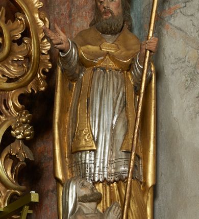 Zdjęcie nr 15: Nastawa ołtarzowa architektoniczna, jednoosiowa, jednokondygnacyjna ze zwieńczeniem, na cokole z czterema prostopadłościennymi postumentami wydzielonymi po bokach, z bramkami. Ołtarz drewniany, prostopadłościenny, z kamienną mensą z portatylem. Antependium drewniane obite miedzianą blachą, w formie leżącego prostokąta, ujętego profilowaną ramą, podzielone na dziesięć pól pasami z ornamentem geometrycznym, oraz aplikami w formie rautów na ich skrzyżowaniu. W środkowym polu monogram Marii oraz dwie apliki z orłem i pogonią u spodu. 
Retabulum flankowane ustawionymi schodkowo i zwróconymi na zewnątrz dwiema parami korynckich kolumn, umieszczonych na tle pilastrów oraz zewnętrzną parą pilastrów dekorowanych kwiatowymi zwisami. Podpory stoją na cokołach, podtrzymują wyłamane belkowanie, przerwane nad polem środkowym, oraz fragmenty przerwanego, falistego przyczółka z siedzącymi na obłokach puttami. W polu środkowym wnęka w formie stojącego prostokąta zamkniętego łukiem półkolistym nadwieszonym z uskokiem w profilowanej ramie, z obrazem św. Marcina. Pole środkowe zamknięte gzymsem przyjmującym kształt łuku odcinkowego nadwieszonego z rokokowym kartuszem z napisem &quot;AVE / MARIA / GRATIA PLENA / LUC. 1.28&quot; oraz z podwieszonymi dwiema różanymi gałązkami. Obraz flankowany dwoma zwisami na wstędze utworzonymi z kwiatów. Kondygnacja ujęta ażurowymi uszami utworzonymi z rocaille&#039;u, kratki i kwiatów. Zwieńczenie w formie zbliżonej po stojącego prostokąta o wklęsłych bokach ujętych spływami wolutowymi z rocaille&#039;m, zamkniętego gzymsem przyjmującym kształt łuku półkolistego nadwieszonego z uskokiem, wyłamanego przy krawędziach, zwieńczonego anthemionem. W polu obraz św. Józefa z Dzieciątkiem w formie zbliżonej do trapezu o wklęsłych bokach i wypukłych podstawach, w ramie. Ujęty z trzech stron wicią roślinną. Bramki na wysokości cokołu nastawy, w formie półkolistych, profilowanych arkad podtrzymywanych na pilastrach o kanelowanych trzonach. Arkady zwieńczone cokołami, na których ustawione są figury św. Wojciecha i św. Stanisława. Struktura polichromowana w kolorze seledynowym, ze złoconymi kolumnami, profilami i ornamentyką.


