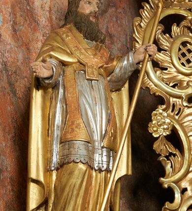 Zdjęcie nr 5: Nastawa ołtarzowa architektoniczna, jednoosiowa, jednokondygnacyjna ze zwieńczeniem, na cokole z czterema prostopadłościennymi postumentami wydzielonymi po bokach, z bramkami. Ołtarz drewniany, prostopadłościenny, z kamienną mensą z portatylem. Antependium drewniane obite miedzianą blachą, w formie leżącego prostokąta, ujętego profilowaną ramą, podzielone na dziesięć pól pasami z ornamentem geometrycznym, oraz aplikami w formie rautów na ich skrzyżowaniu. W środkowym polu monogram Marii oraz dwie apliki z orłem i pogonią u spodu. 
Retabulum flankowane ustawionymi schodkowo i zwróconymi na zewnątrz dwiema parami korynckich kolumn, umieszczonych na tle pilastrów oraz zewnętrzną parą pilastrów dekorowanych kwiatowymi zwisami. Podpory stoją na cokołach, podtrzymują wyłamane belkowanie, przerwane nad polem środkowym, oraz fragmenty przerwanego, falistego przyczółka z siedzącymi na obłokach puttami. W polu środkowym wnęka w formie stojącego prostokąta zamkniętego łukiem półkolistym nadwieszonym z uskokiem w profilowanej ramie, z obrazem św. Marcina. Pole środkowe zamknięte gzymsem przyjmującym kształt łuku odcinkowego nadwieszonego z rokokowym kartuszem z napisem "AVE / MARIA / GRATIA PLENA / LUC. 1.28" oraz z podwieszonymi dwiema różanymi gałązkami. Obraz flankowany dwoma zwisami na wstędze utworzonymi z kwiatów. Kondygnacja ujęta ażurowymi uszami utworzonymi z rocaille'u, kratki i kwiatów. Zwieńczenie w formie zbliżonej po stojącego prostokąta o wklęsłych bokach ujętych spływami wolutowymi z rocaille'm, zamkniętego gzymsem przyjmującym kształt łuku półkolistego nadwieszonego z uskokiem, wyłamanego przy krawędziach, zwieńczonego anthemionem. W polu obraz św. Józefa z Dzieciątkiem w formie zbliżonej do trapezu o wklęsłych bokach i wypukłych podstawach, w ramie. Ujęty z trzech stron wicią roślinną. Bramki na wysokości cokołu nastawy, w formie półkolistych, profilowanych arkad podtrzymywanych na pilastrach o kanelowanych trzonach. Arkady zwieńczone cokołami, na których ustawione są figury św. Wojciecha i św. Stanisława. Struktura polichromowana w kolorze seledynowym, ze złoconymi kolumnami, profilami i ornamentyką.


