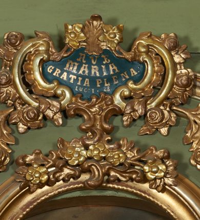 Zdjęcie nr 52: Nastawa ołtarzowa architektoniczna, jednoosiowa, jednokondygnacyjna ze zwieńczeniem, na cokole z czterema prostopadłościennymi postumentami wydzielonymi po bokach, z bramkami. Ołtarz drewniany, prostopadłościenny, z kamienną mensą z portatylem. Antependium drewniane obite miedzianą blachą, w formie leżącego prostokąta, ujętego profilowaną ramą, podzielone na dziesięć pól pasami z ornamentem geometrycznym, oraz aplikami w formie rautów na ich skrzyżowaniu. W środkowym polu monogram Marii oraz dwie apliki z orłem i pogonią u spodu. 
Retabulum flankowane ustawionymi schodkowo i zwróconymi na zewnątrz dwiema parami korynckich kolumn, umieszczonych na tle pilastrów oraz zewnętrzną parą pilastrów dekorowanych kwiatowymi zwisami. Podpory stoją na cokołach, podtrzymują wyłamane belkowanie, przerwane nad polem środkowym, oraz fragmenty przerwanego, falistego przyczółka z siedzącymi na obłokach puttami. W polu środkowym wnęka w formie stojącego prostokąta zamkniętego łukiem półkolistym nadwieszonym z uskokiem w profilowanej ramie, z obrazem św. Marcina. Pole środkowe zamknięte gzymsem przyjmującym kształt łuku odcinkowego nadwieszonego z rokokowym kartuszem z napisem "AVE / MARIA / GRATIA PLENA / LUC. 1.28" oraz z podwieszonymi dwiema różanymi gałązkami. Obraz flankowany dwoma zwisami na wstędze utworzonymi z kwiatów. Kondygnacja ujęta ażurowymi uszami utworzonymi z rocaille'u, kratki i kwiatów. Zwieńczenie w formie zbliżonej po stojącego prostokąta o wklęsłych bokach ujętych spływami wolutowymi z rocaille'm, zamkniętego gzymsem przyjmującym kształt łuku półkolistego nadwieszonego z uskokiem, wyłamanego przy krawędziach, zwieńczonego anthemionem. W polu obraz św. Józefa z Dzieciątkiem w formie zbliżonej do trapezu o wklęsłych bokach i wypukłych podstawach, w ramie. Ujęty z trzech stron wicią roślinną. Bramki na wysokości cokołu nastawy, w formie półkolistych, profilowanych arkad podtrzymywanych na pilastrach o kanelowanych trzonach. Arkady zwieńczone cokołami, na których ustawione są figury św. Wojciecha i św. Stanisława. Struktura polichromowana w kolorze seledynowym, ze złoconymi kolumnami, profilami i ornamentyką.


