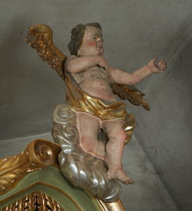 Zdjęcie nr 51: Nastawa ołtarzowa architektoniczna, jednoosiowa, jednokondygnacyjna ze zwieńczeniem, na cokole z czterema prostopadłościennymi postumentami wydzielonymi po bokach, z bramkami. Ołtarz drewniany, prostopadłościenny, z kamienną mensą z portatylem. Antependium drewniane obite miedzianą blachą, w formie leżącego prostokąta, ujętego profilowaną ramą, podzielone na dziesięć pól pasami z ornamentem geometrycznym, oraz aplikami w formie rautów na ich skrzyżowaniu. W środkowym polu monogram Marii oraz dwie apliki z orłem i pogonią u spodu. 
Retabulum flankowane ustawionymi schodkowo i zwróconymi na zewnątrz dwiema parami korynckich kolumn, umieszczonych na tle pilastrów oraz zewnętrzną parą pilastrów dekorowanych kwiatowymi zwisami. Podpory stoją na cokołach, podtrzymują wyłamane belkowanie, przerwane nad polem środkowym, oraz fragmenty przerwanego, falistego przyczółka z siedzącymi na obłokach puttami. W polu środkowym wnęka w formie stojącego prostokąta zamkniętego łukiem półkolistym nadwieszonym z uskokiem w profilowanej ramie, z obrazem św. Marcina. Pole środkowe zamknięte gzymsem przyjmującym kształt łuku odcinkowego nadwieszonego z rokokowym kartuszem z napisem "AVE / MARIA / GRATIA PLENA / LUC. 1.28" oraz z podwieszonymi dwiema różanymi gałązkami. Obraz flankowany dwoma zwisami na wstędze utworzonymi z kwiatów. Kondygnacja ujęta ażurowymi uszami utworzonymi z rocaille'u, kratki i kwiatów. Zwieńczenie w formie zbliżonej po stojącego prostokąta o wklęsłych bokach ujętych spływami wolutowymi z rocaille'm, zamkniętego gzymsem przyjmującym kształt łuku półkolistego nadwieszonego z uskokiem, wyłamanego przy krawędziach, zwieńczonego anthemionem. W polu obraz św. Józefa z Dzieciątkiem w formie zbliżonej do trapezu o wklęsłych bokach i wypukłych podstawach, w ramie. Ujęty z trzech stron wicią roślinną. Bramki na wysokości cokołu nastawy, w formie półkolistych, profilowanych arkad podtrzymywanych na pilastrach o kanelowanych trzonach. Arkady zwieńczone cokołami, na których ustawione są figury św. Wojciecha i św. Stanisława. Struktura polichromowana w kolorze seledynowym, ze złoconymi kolumnami, profilami i ornamentyką.


