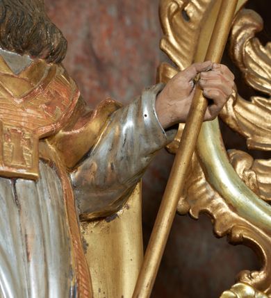 Zdjęcie nr 14: Nastawa ołtarzowa architektoniczna, jednoosiowa, jednokondygnacyjna ze zwieńczeniem, na cokole z czterema prostopadłościennymi postumentami wydzielonymi po bokach, z bramkami. Ołtarz drewniany, prostopadłościenny, z kamienną mensą z portatylem. Antependium drewniane obite miedzianą blachą, w formie leżącego prostokąta, ujętego profilowaną ramą, podzielone na dziesięć pól pasami z ornamentem geometrycznym, oraz aplikami w formie rautów na ich skrzyżowaniu. W środkowym polu monogram Marii oraz dwie apliki z orłem i pogonią u spodu. 
Retabulum flankowane ustawionymi schodkowo i zwróconymi na zewnątrz dwiema parami korynckich kolumn, umieszczonych na tle pilastrów oraz zewnętrzną parą pilastrów dekorowanych kwiatowymi zwisami. Podpory stoją na cokołach, podtrzymują wyłamane belkowanie, przerwane nad polem środkowym, oraz fragmenty przerwanego, falistego przyczółka z siedzącymi na obłokach puttami. W polu środkowym wnęka w formie stojącego prostokąta zamkniętego łukiem półkolistym nadwieszonym z uskokiem w profilowanej ramie, z obrazem św. Marcina. Pole środkowe zamknięte gzymsem przyjmującym kształt łuku odcinkowego nadwieszonego z rokokowym kartuszem z napisem "AVE / MARIA / GRATIA PLENA / LUC. 1.28" oraz z podwieszonymi dwiema różanymi gałązkami. Obraz flankowany dwoma zwisami na wstędze utworzonymi z kwiatów. Kondygnacja ujęta ażurowymi uszami utworzonymi z rocaille'u, kratki i kwiatów. Zwieńczenie w formie zbliżonej po stojącego prostokąta o wklęsłych bokach ujętych spływami wolutowymi z rocaille'm, zamkniętego gzymsem przyjmującym kształt łuku półkolistego nadwieszonego z uskokiem, wyłamanego przy krawędziach, zwieńczonego anthemionem. W polu obraz św. Józefa z Dzieciątkiem w formie zbliżonej do trapezu o wklęsłych bokach i wypukłych podstawach, w ramie. Ujęty z trzech stron wicią roślinną. Bramki na wysokości cokołu nastawy, w formie półkolistych, profilowanych arkad podtrzymywanych na pilastrach o kanelowanych trzonach. Arkady zwieńczone cokołami, na których ustawione są figury św. Wojciecha i św. Stanisława. Struktura polichromowana w kolorze seledynowym, ze złoconymi kolumnami, profilami i ornamentyką.



