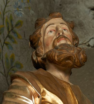 Zdjęcie nr 9: Nastawa ołtarzowa architektoniczna, jednoosiowa, jednokondygnacyjna ze zwieńczeniem, ustawiona na cokole z dwoma prostopadłościennymi postumentami wydzielonymi po bokach, z bramkami w partii cokołu. Ołtarz drewniany, prostopadłościenny, zwężający się ku dołowi, dekorowany z przodu rzeźbionym wieńcem z monogramem Marii, mensa drewniana. Na mensie ustawione tabernakulum w formie drewnianej skrzynki o ściętych przednich narożach, flankowanej parą kolumienek. Drzwiczki w formie stojącego prostokąta dekorowane płyciną. Nastawa ołtarzowa ujęta parą kolumn o stylizowanych kapitelach kompozytowych dźwigających pełne belkowanie, przerwane nad polem środkowym, oraz fragmenty przerwanego, półkolistego przyczółka, na którym klęczą na obłokach dwa putta. Fryz dekorowany ornamentem roślinnym zbliżonym do akantu. W polu głównym wnęka w formie stojącego prostokąta w profilowanej ramie, z obrazem Koronacji Marii. Nad nim medalion utworzony z akantu z monogramem Marii, zwieńczony koroną zamkniętą. Zwieńczenie w formie trapezu, którego brzegi dekorowane są stylizowanym rocaille&#039;m tworzącym uszaki. W polu obraz św. Józefa w formie trapezu o ściętych dolnych narożach, zamkniętego łukiem półkolistym nadwieszonym, w profilowanej ramie, z łukiem częściowo przesłoniętym obłokami z dwoma uskrzydlonymi główkami anielskimi. Nastawa zakończona medalionem z obłoków z Okiem Opatrzności w glorii promienistej. Nastawę flankują bramki w partii cokołu z przejściami w formie stojącego prostokąta zamkniętego łukiem odcinkowym nadwieszonym, zakończone profilowanym gzymsem oraz cokołami dekorowanymi roślinnymi konsolami, na których stoją figury św. Anny i św. Joachima. Struktura polichromowana w kolorze seledynowym, ze złoconymi kolumnami, profilami i  ornamentyką. 
