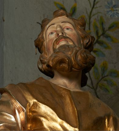 Zdjęcie nr 8: Nastawa ołtarzowa architektoniczna, jednoosiowa, jednokondygnacyjna ze zwieńczeniem, ustawiona na cokole z dwoma prostopadłościennymi postumentami wydzielonymi po bokach, z bramkami w partii cokołu. Ołtarz drewniany, prostopadłościenny, zwężający się ku dołowi, dekorowany z przodu rzeźbionym wieńcem z monogramem Marii, mensa drewniana. Na mensie ustawione tabernakulum w formie drewnianej skrzynki o ściętych przednich narożach, flankowanej parą kolumienek. Drzwiczki w formie stojącego prostokąta dekorowane płyciną. Nastawa ołtarzowa ujęta parą kolumn o stylizowanych kapitelach kompozytowych dźwigających pełne belkowanie, przerwane nad polem środkowym, oraz fragmenty przerwanego, półkolistego przyczółka, na którym klęczą na obłokach dwa putta. Fryz dekorowany ornamentem roślinnym zbliżonym do akantu. W polu głównym wnęka w formie stojącego prostokąta w profilowanej ramie, z obrazem Koronacji Marii. Nad nim medalion utworzony z akantu z monogramem Marii, zwieńczony koroną zamkniętą. Zwieńczenie w formie trapezu, którego brzegi dekorowane są stylizowanym rocaille&#039;m tworzącym uszaki. W polu obraz św. Józefa w formie trapezu o ściętych dolnych narożach, zamkniętego łukiem półkolistym nadwieszonym, w profilowanej ramie, z łukiem częściowo przesłoniętym obłokami z dwoma uskrzydlonymi główkami anielskimi. Nastawa zakończona medalionem z obłoków z Okiem Opatrzności w glorii promienistej. Nastawę flankują bramki w partii cokołu z przejściami w formie stojącego prostokąta zamkniętego łukiem odcinkowym nadwieszonym, zakończone profilowanym gzymsem oraz cokołami dekorowanymi roślinnymi konsolami, na których stoją figury św. Anny i św. Joachima. Struktura polichromowana w kolorze seledynowym, ze złoconymi kolumnami, profilami i  ornamentyką. 
