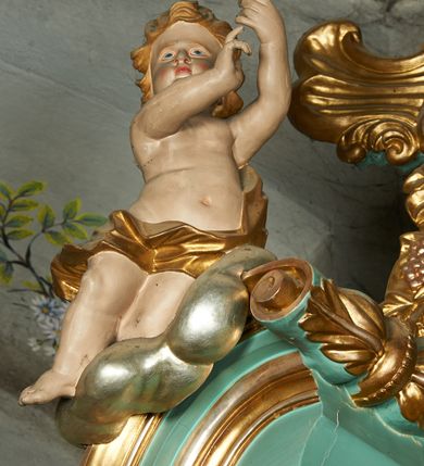 Zdjęcie nr 14: Nastawa ołtarzowa architektoniczna, jednoosiowa, jednokondygnacyjna ze zwieńczeniem, ustawiona na cokole z dwoma prostopadłościennymi postumentami wydzielonymi po bokach, z bramkami w partii cokołu. Ołtarz drewniany, prostopadłościenny, zwężający się ku dołowi, dekorowany z przodu rzeźbionym wieńcem z monogramem Marii, mensa drewniana. Na mensie ustawione tabernakulum w formie drewnianej skrzynki o ściętych przednich narożach, flankowanej parą kolumienek. Drzwiczki w formie stojącego prostokąta dekorowane płyciną. Nastawa ołtarzowa ujęta parą kolumn o stylizowanych kapitelach kompozytowych dźwigających pełne belkowanie, przerwane nad polem środkowym, oraz fragmenty przerwanego, półkolistego przyczółka, na którym klęczą na obłokach dwa putta. Fryz dekorowany ornamentem roślinnym zbliżonym do akantu. W polu głównym wnęka w formie stojącego prostokąta w profilowanej ramie, z obrazem Koronacji Marii. Nad nim medalion utworzony z akantu z monogramem Marii, zwieńczony koroną zamkniętą. Zwieńczenie w formie trapezu, którego brzegi dekorowane są stylizowanym rocaille'm tworzącym uszaki. W polu obraz św. Józefa w formie trapezu o ściętych dolnych narożach, zamkniętego łukiem półkolistym nadwieszonym, w profilowanej ramie, z łukiem częściowo przesłoniętym obłokami z dwoma uskrzydlonymi główkami anielskimi. Nastawa zakończona medalionem z obłoków z Okiem Opatrzności w glorii promienistej. Nastawę flankują bramki w partii cokołu z przejściami w formie stojącego prostokąta zamkniętego łukiem odcinkowym nadwieszonym, zakończone profilowanym gzymsem oraz cokołami dekorowanymi roślinnymi konsolami, na których stoją figury św. Anny i św. Joachima. Struktura polichromowana w kolorze seledynowym, ze złoconymi kolumnami, profilami i  ornamentyką. 
