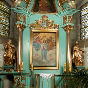 Zdjęcie nr 1: Nastawa ołtarzowa architektoniczna, jednoosiowa, jednokondygnacyjna ze zwieńczeniem, ustawiona na cokole z dwoma prostopadłościennymi postumentami wydzielonymi po bokach, z bramkami w partii cokołu. Ołtarz drewniany, prostopadłościenny, zwężający się ku dołowi, dekorowany z przodu rzeźbionym wieńcem z monogramem Marii, mensa drewniana. Na mensie ustawione tabernakulum w formie drewnianej skrzynki o ściętych przednich narożach, flankowanej parą kolumienek. Drzwiczki w formie stojącego prostokąta dekorowane płyciną. Nastawa ołtarzowa ujęta parą kolumn o stylizowanych kapitelach kompozytowych dźwigających pełne belkowanie, przerwane nad polem środkowym, oraz fragmenty przerwanego, półkolistego przyczółka, na którym klęczą na obłokach dwa putta. Fryz dekorowany ornamentem roślinnym zbliżonym do akantu. W polu głównym wnęka w formie stojącego prostokąta w profilowanej ramie, z obrazem Koronacji Marii. Nad nim medalion utworzony z akantu z monogramem Marii, zwieńczony koroną zamkniętą. Zwieńczenie w formie trapezu, którego brzegi dekorowane są stylizowanym rocaille'm tworzącym uszaki. W polu obraz św. Józefa w formie trapezu o ściętych dolnych narożach, zamkniętego łukiem półkolistym nadwieszonym, w profilowanej ramie, z łukiem częściowo przesłoniętym obłokami z dwoma uskrzydlonymi główkami anielskimi. Nastawa zakończona medalionem z obłoków z Okiem Opatrzności w glorii promienistej. Nastawę flankują bramki w partii cokołu z przejściami w formie stojącego prostokąta zamkniętego łukiem odcinkowym nadwieszonym, zakończone profilowanym gzymsem oraz cokołami dekorowanymi roślinnymi konsolami, na których stoją figury św. Anny i św. Joachima. Struktura polichromowana w kolorze seledynowym, ze złoconymi kolumnami, profilami i  ornamentyką. 
