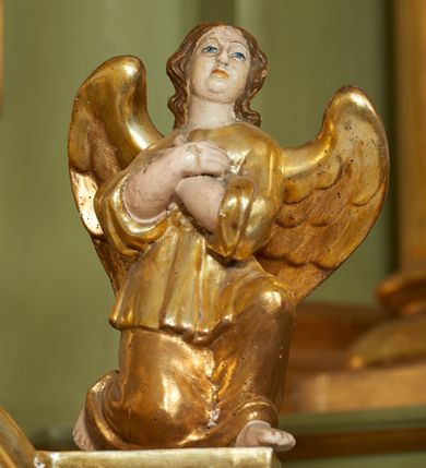 Zdjęcie nr 3: Tabernakulum w formie drewnianej skrzynki ustawionej na niskiej podstawie, ujęte w czterech narożach ukośnie zwróconymi cokołami z kolumnami dźwigającymi imposty oraz profilowany gzyms opasujący całość, nad ścianką frontową przyjmujący kształt łuku odcinkowego. Drzwiczki w formie stojącego prostokąta zamkniętego łukiem półkolistym, dekorowane płaskorzeźbionym przedstawieniem kielicha z hostią, flankowanego winnym gronem i kłosami zbóż. Drzwiczki ujęte z trzech stron ornamentem roślinnym. Na gzymsie dwie figurki klęczących  aniołów. Tabernakulum w całości pozłocone. 

