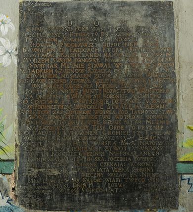 Zdjęcie nr 2: Płyta w formie stojącego prostokąta. W polu złocona inskrypcja: „D[EO] O[PTIMO] M[AXIMO] / ZIMNY MARMVR POKRIWAM PROCHV MIZERNEGO / SCZVPLA RESZTE KTORA TV DNIA CZEKA SADNEGO. / TE SZYMON Z KALINOWA KALINOWSKI W GROBIE / ZŁOZYŁ VPODOBAWSZY ODPOCYNEK SOBIE / PO WOIENNYCH FATIGACH KTORE Z KONIECPOLSKIEM / ZOSTAIAC KASTELANEM NA ONCZASZ KRAKOWSKIM / WODZEM SWOIM PONOSIEŁ MALBORSKIE SWIADKAMI / MVRY IAK MEZNIE STAWIAŁ W BITWIE ZE SZWEDA[M]I / SWIADKIEM CZVDNOW KOZACKA GDZIE SPRZISIEGŁA SIE A / ZDVMNEM MOSKALEM ZGVBE OYCZYZNIE WROZYŁA / IAK KAWALERSKO STAWAŁ GDZIE PRZESZ WOYSKA MESTWO / WSPANIAŁE ODEBRAŁA KORONA ZWYCIESTWO / POTYM GDY NOWE BVNTY KOZACZTWO WZNIECIEŁO / ZA DNIEPREM A WOYSKO SIE KORONNE SKUPIEŁO / POD GŁVCHOW BYŁ W POTRZEBIE DZIELNOSC V WAZONO / I W PODNIESTRZV ZAWODZIC STRAZE  MV ZLECONO. / W PRETCZE  ZAS GDY CZESC WOISKA POD TARNOPOL STAWA / WODZ IEMV STRAZNIKOSTWO WOYSKOWE ODDAWA / Z POCHWAŁA TO ODPRAWIEŁ BIEŁ SIE POTYM MEZNIE / NA BATOHV Z TATARY TESZ ORDE POTESZNIE / POD KALVSZA KVMARNEM GROMIEŁ YZ TVRKAMI / VGANIAŁ SIE WIELEKROC WSZYKV Y HARCAMI / SKONCZYŁ WOYNE KRWIA TVRSKA POLA NAPOIWSZY / CHOCIMSKIE A ZIEMIANSKI ZYWOT VLVBIWSZY / W TYM KOSCIELE GOEZINKI NIEPOKALANEGO / FVNDOWAŁ MATKO BOSKA POCZECIA TWOIEGO. / WIEC ZA TRVDY WOIENNE CZEKAIAC KORONY / DO TWEI SIE PANI SWIATA VCIEKA OBRONY / VPROS MV ZYWOT WIECZNY WSZAK MV NIENOWINA / BYLO LAC KREW ZA CALOSC WIARY TWEGO SYNA / VMARŁ DNIA [...] ROKV [...] / WIEKV SWEGO LAT [...]”. W górnym lewym rogu płyty ryty herb Ślepowron z inskrypcją: „[Z DOMV KALINOWSKI]CH ZRODZICA”. W górnym prawym rogu ryty herb Gozdawa z inskrypcją: „[Z DOMV SOKO]/LOWSKICH ZM[ATKI]”. W dolnym lewym rogu herb Pilawa z inskrypcją: „[Z] DOMV POROWSK/[I]CH PRABABY”. W dolnym prawym rogu herb Massalski z inskrypcją: „Z DOMV MASS/ALSKICH ZBABY”. 


