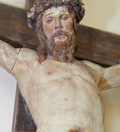 Zdjęcie nr 5: Figura Chrystusa żywego przybitego trzema gwoździami do prostego krzyża. Ciało w lekkim zwisie, o szeroko rozłożonych ramionach, lekko łukowato wygiętych, głowa przechylona na prawy bark, nogi wyprostowane, stopy skrzyżowane w układzie prawa na lewą. Twarz ma podłużną, o półprzymkniętych oczach, małym nosie i pełnych ustach, okoloną falowaną brodą i włosami sięgającymi ramion. Na głowie korona cierniowa. Ciało szczupłe, muskularne, o delikatnie podkreślonym modelunku klatki piersiowej i ramion. Biodra przesłonięte obszernym, silnie drapowanym, białym perizonium ze złoconą lamówką, sięgającym połowy uda, zawiązanym na prawym boku, z długim zwisem tkaniny wzdłuż prawej nogi. Polichromia ciała naturalistyczna z zaznaczonymi śladami męki. 