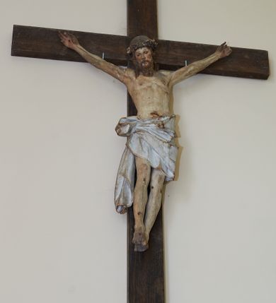 Zdjęcie nr 3: Figura Chrystusa żywego przybitego trzema gwoździami do prostego krzyża. Ciało w lekkim zwisie, o szeroko rozłożonych ramionach, lekko łukowato wygiętych, głowa przechylona na prawy bark, nogi wyprostowane, stopy skrzyżowane w układzie prawa na lewą. Twarz ma podłużną, o półprzymkniętych oczach, małym nosie i pełnych ustach, okoloną falowaną brodą i włosami sięgającymi ramion. Na głowie korona cierniowa. Ciało szczupłe, muskularne, o delikatnie podkreślonym modelunku klatki piersiowej i ramion. Biodra przesłonięte obszernym, silnie drapowanym, białym perizonium ze złoconą lamówką, sięgającym połowy uda, zawiązanym na prawym boku, z długim zwisem tkaniny wzdłuż prawej nogi. Polichromia ciała naturalistyczna z zaznaczonymi śladami męki. 