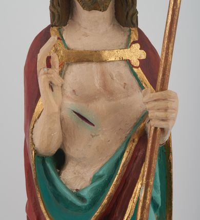 Zdjęcie nr 4: Figura Chrystusa pełnoplastyczna, ustawiona na podstawie na planie ośmioboku oraz na rzeźbionym fragmencie podłoża. Chrystus zwrócony jest frontalnie, w lekkim kontrapoście. Prawą rękę unosi w geście błogosławieństwa, w lewej trzyma drzewce czerwonej chorągwi z tkaniny z naszytym krzyżem, ujętej dwoma chwostami. Twarz ma pociągłą z wysokim czołem, migdałowatymi oczami, wąskim i zadartym nosem oraz małymi ustami, okoloną krótką, falowaną brodą rozdzieloną na dwoje oraz regularnie falowanymi włosami sięgającymi ramion. Ubrany jest w czerwony płaszcz z zieloną podszewką i złoconą lamówką, zapięty na piersi, opadający na plecy i ramiona, zawinięty łukowato z przodu postaci, odsłaniający nagi tors i lewą nogę. Polichromia ciała naturalistyczna z zaznaczonymi śladami męki.