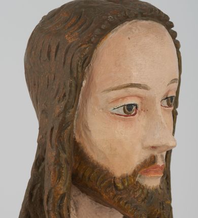 Zdjęcie nr 5: Figura Chrystusa pełnoplastyczna, ustawiona na podstawie na planie ośmioboku oraz na rzeźbionym fragmencie podłoża. Chrystus zwrócony jest frontalnie, w lekkim kontrapoście. Prawą rękę unosi w geście błogosławieństwa, w lewej trzyma drzewce czerwonej chorągwi z tkaniny z naszytym krzyżem, ujętej dwoma chwostami. Twarz ma pociągłą z wysokim czołem, migdałowatymi oczami, wąskim i zadartym nosem oraz małymi ustami, okoloną krótką, falowaną brodą rozdzieloną na dwoje oraz regularnie falowanymi włosami sięgającymi ramion. Ubrany jest w czerwony płaszcz z zieloną podszewką i złoconą lamówką, zapięty na piersi, opadający na plecy i ramiona, zawinięty łukowato z przodu postaci, odsłaniający nagi tors i lewą nogę. Polichromia ciała naturalistyczna z zaznaczonymi śladami męki.