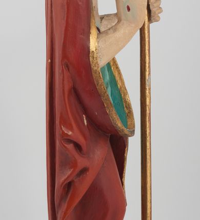 Zdjęcie nr 2: Figura Chrystusa pełnoplastyczna, ustawiona na podstawie na planie ośmioboku oraz na rzeźbionym fragmencie podłoża. Chrystus zwrócony jest frontalnie, w lekkim kontrapoście. Prawą rękę unosi w geście błogosławieństwa, w lewej trzyma drzewce czerwonej chorągwi z tkaniny z naszytym krzyżem, ujętej dwoma chwostami. Twarz ma pociągłą z wysokim czołem, migdałowatymi oczami, wąskim i zadartym nosem oraz małymi ustami, okoloną krótką, falowaną brodą rozdzieloną na dwoje oraz regularnie falowanymi włosami sięgającymi ramion. Ubrany jest w czerwony płaszcz z zieloną podszewką i złoconą lamówką, zapięty na piersi, opadający na plecy i ramiona, zawinięty łukowato z przodu postaci, odsłaniający nagi tors i lewą nogę. Polichromia ciała naturalistyczna z zaznaczonymi śladami męki.