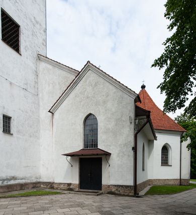 Zdjęcie nr 2: Kościół murowany z cegły i kamienia, tynkowany, orientowany, jednonawowy z kaplicami. Prezbiterium wydłużone, zamknięte trójbocznie, odchylone na południe od osi nawy, przy północnej ścianie niewielka, prostokątna dawna zakrystia (obecnie kruchta), przy południowej dobudowana wtórnie piętrowa dwuczęściowa zakrystia ze skarbcem, od wschodu, na zewnętrznej ścianie kościoła Ogrojec. Nawa główna szersza od prezbiterium, na rzucie prostokąta, od południa wieloboczna kaplica Najświętszego Serca Pana Jezusa (dawniej Przemienienia Pańskiego), od północy i południa dobudowane kaplice boczne na planie prostokąta, północna dwukrotnie większa od południowej, od zachodu wieża na planie kwadratu. Prezbiterium i nawa nakryte sklepieniami pozornymi, oddzielone od ścian gzymsem przebiegającym przez całe wnętrze, łuk tęczowy półkolisty, wewnątrz ujęty pilastrami. Dawne, ostrołukowe okna znajdują się w ścianach nawy głównej. Dostęp do kaplicy i naw bocznych z nawy głównej przez wysokie przejścia arkadowe, w północnej części nawy ujęte opaskami tynkowymi, w północno-zachodniej przejście z barokowym, kamiennym portalem (dawne wejście do kościoła). W starej zakrystii dwa gotyckie, kamienne, ostrołukowe portale oraz gotyckie okno. W wielobocznej kaplicy sklepienie kolebkowe z lunetami, w kaplicach bocznych oraz w nowej zakrystii stropy żelbetowe i sufity tynkowe. Elewacje tynkowane, z obłożoną kamieniem partią cokołu, ściana północna dawnej zakrystii z odsłoniętym wątkiem kamiennym oraz narożną przyporą, wieloboczna kaplica oszkarpowana w narożach. Do wschodniej ściany prezbiterium dobudowany kamienny Ogrójec z arkadą, zwieńczony gzymsem oraz schodkowym szczytem z kamiennymi figurami. Wejścia do kościoła przez kaplice boczne od północy i zachodu oraz przez kruchtę w przyziemiu wieży. Okna w formie stojącego prostokąta w ścianach kaplic bocznych, nowej zakrystii, prezbiterium, okna ostrołukowe w wielobocznej kaplicy. Wieża smukła, trójkondygnacyjna, bez podziałów architektonicznych z oknami na poziomie każdej kondygnacji, zwieńczona hełmem baniastym. Nawa główna i prezbiterium nakryte dachem dwuspadowym, niższe nawy boczne również. W miejscu połączenia nawy i prezbiterium wieżyczka na sygnaturkę. Kaplica przekryta dachem ostrosłupowym, nowa zakrystia i skarbiec dachem trójspadowym, stara zakrystia pulpitowym. 
