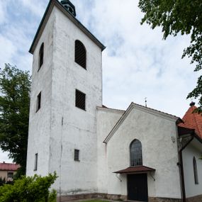 Zdjęcie nr 1: Kościół murowany z cegły i kamienia, tynkowany, orientowany, jednonawowy z kaplicami. Prezbiterium wydłużone, zamknięte trójbocznie, odchylone na południe od osi nawy, przy północnej ścianie niewielka, prostokątna dawna zakrystia (obecnie kruchta), przy południowej dobudowana wtórnie piętrowa dwuczęściowa zakrystia ze skarbcem, od wschodu, na zewnętrznej ścianie kościoła Ogrojec. Nawa główna szersza od prezbiterium, na rzucie prostokąta, od południa wieloboczna kaplica Najświętszego Serca Pana Jezusa (dawniej Przemienienia Pańskiego), od północy i południa dobudowane kaplice boczne na planie prostokąta, północna dwukrotnie większa od południowej, od zachodu wieża na planie kwadratu. Prezbiterium i nawa nakryte sklepieniami pozornymi, oddzielone od ścian gzymsem przebiegającym przez całe wnętrze, łuk tęczowy półkolisty, wewnątrz ujęty pilastrami. Dawne, ostrołukowe okna znajdują się w ścianach nawy głównej. Dostęp do kaplicy i naw bocznych z nawy głównej przez wysokie przejścia arkadowe, w północnej części nawy ujęte opaskami tynkowymi, w północno-zachodniej przejście z barokowym, kamiennym portalem (dawne wejście do kościoła). W starej zakrystii dwa gotyckie, kamienne, ostrołukowe portale oraz gotyckie okno. W wielobocznej kaplicy sklepienie kolebkowe z lunetami, w kaplicach bocznych oraz w nowej zakrystii stropy żelbetowe i sufity tynkowe. Elewacje tynkowane, z obłożoną kamieniem partią cokołu, ściana północna dawnej zakrystii z odsłoniętym wątkiem kamiennym oraz narożną przyporą, wieloboczna kaplica oszkarpowana w narożach. Do wschodniej ściany prezbiterium dobudowany kamienny Ogrójec z arkadą, zwieńczony gzymsem oraz schodkowym szczytem z kamiennymi figurami. Wejścia do kościoła przez kaplice boczne od północy i zachodu oraz przez kruchtę w przyziemiu wieży. Okna w formie stojącego prostokąta w ścianach kaplic bocznych, nowej zakrystii, prezbiterium, okna ostrołukowe w wielobocznej kaplicy. Wieża smukła, trójkondygnacyjna, bez podziałów architektonicznych z oknami na poziomie każdej kondygnacji, zwieńczona hełmem baniastym. Nawa główna i prezbiterium nakryte dachem dwuspadowym, niższe nawy boczne również. W miejscu połączenia nawy i prezbiterium wieżyczka na sygnaturkę. Kaplica przekryta dachem ostrosłupowym, nowa zakrystia i skarbiec dachem trójspadowym, stara zakrystia pulpitowym. 
