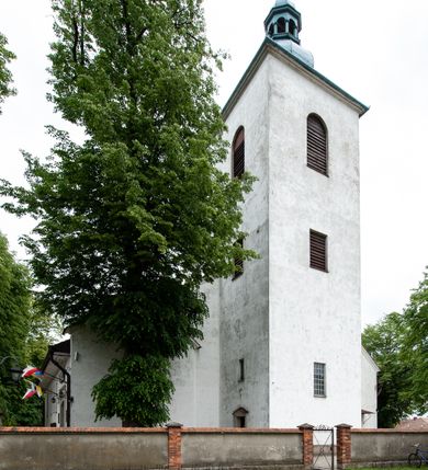 Zdjęcie nr 20: Kościół murowany z cegły i kamienia, tynkowany, orientowany, jednonawowy z kaplicami. Prezbiterium wydłużone, zamknięte trójbocznie, odchylone na południe od osi nawy, przy północnej ścianie niewielka, prostokątna dawna zakrystia (obecnie kruchta), przy południowej dobudowana wtórnie piętrowa dwuczęściowa zakrystia ze skarbcem, od wschodu, na zewnętrznej ścianie kościoła Ogrojec. Nawa główna szersza od prezbiterium, na rzucie prostokąta, od południa wieloboczna kaplica Najświętszego Serca Pana Jezusa (dawniej Przemienienia Pańskiego), od północy i południa dobudowane kaplice boczne na planie prostokąta, północna dwukrotnie większa od południowej, od zachodu wieża na planie kwadratu. Prezbiterium i nawa nakryte sklepieniami pozornymi, oddzielone od ścian gzymsem przebiegającym przez całe wnętrze, łuk tęczowy półkolisty, wewnątrz ujęty pilastrami. Dawne, ostrołukowe okna znajdują się w ścianach nawy głównej. Dostęp do kaplicy i naw bocznych z nawy głównej przez wysokie przejścia arkadowe, w północnej części nawy ujęte opaskami tynkowymi, w północno-zachodniej przejście z barokowym, kamiennym portalem (dawne wejście do kościoła). W starej zakrystii dwa gotyckie, kamienne, ostrołukowe portale oraz gotyckie okno. W wielobocznej kaplicy sklepienie kolebkowe z lunetami, w kaplicach bocznych oraz w nowej zakrystii stropy żelbetowe i sufity tynkowe. Elewacje tynkowane, z obłożoną kamieniem partią cokołu, ściana północna dawnej zakrystii z odsłoniętym wątkiem kamiennym oraz narożną przyporą, wieloboczna kaplica oszkarpowana w narożach. Do wschodniej ściany prezbiterium dobudowany kamienny Ogrójec z arkadą, zwieńczony gzymsem oraz schodkowym szczytem z kamiennymi figurami. Wejścia do kościoła przez kaplice boczne od północy i zachodu oraz przez kruchtę w przyziemiu wieży. Okna w formie stojącego prostokąta w ścianach kaplic bocznych, nowej zakrystii, prezbiterium, okna ostrołukowe w wielobocznej kaplicy. Wieża smukła, trójkondygnacyjna, bez podziałów architektonicznych z oknami na poziomie każdej kondygnacji, zwieńczona hełmem baniastym. Nawa główna i prezbiterium nakryte dachem dwuspadowym, niższe nawy boczne również. W miejscu połączenia nawy i prezbiterium wieżyczka na sygnaturkę. Kaplica przekryta dachem ostrosłupowym, nowa zakrystia i skarbiec dachem trójspadowym, stara zakrystia pulpitowym. 
