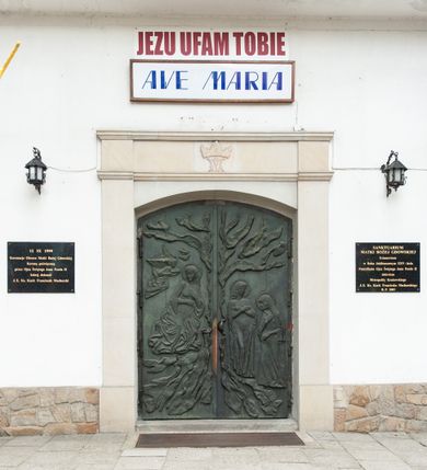 Zdjęcie nr 10: Kościół murowany z cegły i kamienia, tynkowany, orientowany, jednonawowy z kaplicami. Prezbiterium wydłużone, zamknięte trójbocznie, odchylone na południe od osi nawy, przy północnej ścianie niewielka, prostokątna dawna zakrystia (obecnie kruchta), przy południowej dobudowana wtórnie piętrowa dwuczęściowa zakrystia ze skarbcem, od wschodu, na zewnętrznej ścianie kościoła Ogrojec. Nawa główna szersza od prezbiterium, na rzucie prostokąta, od południa wieloboczna kaplica Najświętszego Serca Pana Jezusa (dawniej Przemienienia Pańskiego), od północy i południa dobudowane kaplice boczne na planie prostokąta, północna dwukrotnie większa od południowej, od zachodu wieża na planie kwadratu. Prezbiterium i nawa nakryte sklepieniami pozornymi, oddzielone od ścian gzymsem przebiegającym przez całe wnętrze, łuk tęczowy półkolisty, wewnątrz ujęty pilastrami. Dawne, ostrołukowe okna znajdują się w ścianach nawy głównej. Dostęp do kaplicy i naw bocznych z nawy głównej przez wysokie przejścia arkadowe, w północnej części nawy ujęte opaskami tynkowymi, w północno-zachodniej przejście z barokowym, kamiennym portalem (dawne wejście do kościoła). W starej zakrystii dwa gotyckie, kamienne, ostrołukowe portale oraz gotyckie okno. W wielobocznej kaplicy sklepienie kolebkowe z lunetami, w kaplicach bocznych oraz w nowej zakrystii stropy żelbetowe i sufity tynkowe. Elewacje tynkowane, z obłożoną kamieniem partią cokołu, ściana północna dawnej zakrystii z odsłoniętym wątkiem kamiennym oraz narożną przyporą, wieloboczna kaplica oszkarpowana w narożach. Do wschodniej ściany prezbiterium dobudowany kamienny Ogrójec z arkadą, zwieńczony gzymsem oraz schodkowym szczytem z kamiennymi figurami. Wejścia do kościoła przez kaplice boczne od północy i zachodu oraz przez kruchtę w przyziemiu wieży. Okna w formie stojącego prostokąta w ścianach kaplic bocznych, nowej zakrystii, prezbiterium, okna ostrołukowe w wielobocznej kaplicy. Wieża smukła, trójkondygnacyjna, bez podziałów architektonicznych z oknami na poziomie każdej kondygnacji, zwieńczona hełmem baniastym. Nawa główna i prezbiterium nakryte dachem dwuspadowym, niższe nawy boczne również. W miejscu połączenia nawy i prezbiterium wieżyczka na sygnaturkę. Kaplica przekryta dachem ostrosłupowym, nowa zakrystia i skarbiec dachem trójspadowym, stara zakrystia pulpitowym. 
