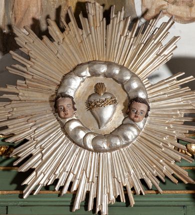 Zdjęcie nr 15: Nastawa architektoniczna, jednoosiowa, dwukondygnacyjna, ustawiona na niewielkim cokole. Ołtarz drewniany, prostopadłościenny, z drewnianą mensą, ustawiony na dwustopniowej podstawie. Antepedium ujęte ramą, w jego polu płycina dekorowana w narożach ornamentem roślinnym, pośrodku medalion z monogramem IHS w glorii promienistej. Na ołtarzu ustawione jest tabernakulum w formie drewnianej skrzynki flankowanej półwalcami oraz falistymi spływami z nałożonymi płaskorzeźbionymi postaciami adorujących puttów. Drzwiczki w kształcie stojącego prostokąta zamkniętego łukiem segmentowym nadwieszonym z kielichem i hostią w polu. 
Pierwsza kondygnacja flankowana jest zwielokrotnionymi pilastrami i stojącą przed nimi parą kolumn o kapitelach kompozytowych, dźwigających pełne belkowanie, z gzymsem dekorowanym kimationem, wyłamane na ich osi, z przerwanym architrawem nad polem środkowym. Na belkowaniu, na osiach kolumn przerwany, falisty przyczółek. W polu środkowym nisza w kształcie stojącego prostokąta zamkniętego łukiem segmentowym nadwieszonym, ujęta profilowaną ramą z obrazem Najświętszego Serca Pana Jezusa w formie stojącego prostokąta w osobnej, profilowanej ramie. Druga kondygnacja ustawiona na niewielkim cokole, flankowana zdwojonymi pilastrami i stojącą przed nimi parą kolumn o kapitelach kompozytowych, dźwigających pełne belkowanie z gzymsem dekorowanym kimationem, wyłamane na ich osi oraz przerwany półkolisty przyczółek. Nad polem, w partii belkowania medalion z przedstawieniem Gorejącego Serca w glorii promienistej, flankowany główkami anielskimi. W polu obraz w kształcie stojącego prostokąta ujętego profilowaną rama z przedstawieniem św. Franciszka obejmującego Chrystusa na krzyżu (amplexus). Obie kondygnacje ujęte uszami, pierwsza utworzonymi ze stylizowanego akantu, druga ze stylizowanego ornamentu roślinnego. Cokoły i belkowanie pierwszej kondygnacji dekorowane stylizowanym ornamentem roślinnym. Struktura ołtarza polichromowana w kolorze jasnozielonym, kolumny i profile pozłocone, ornamentyka pozłocona i posrebrzona. 