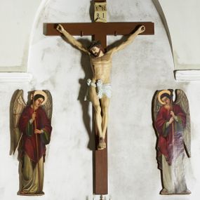 Zdjęcie nr 1: Figura umarłego Chrystusa przybita trzema gwoździami do krzyża o prostym zakończeniu ramion. Ciało w dużym zwisie, o ramionach przyjmujących kształt szerokiego „V”, na lekko ugiętych nogach, ze stopami skrzyżowanymi w układzie prawa na lewą, głowa opada na prawy bark. Twarz ma szczupłą, o dużych, zamkniętych oczach, wąskim nosie i ustach, okoloną krótką brodą i brązowymi włosami, sięgającymi ramion. Na głowie ma koronę cierniową. Ciało ma szczupłe i umięśnione, zwłaszcza w partii ramion i nóg, klatka piersiowa o delikatnie podkreślonej muskulaturze. W prawym boku rana z rzeźbionymi kroplami krwi. Białe, krótkie perizonium zawieszone na podwójnym sznurze, odsłaniające prawe udo, ze zwisem tkaniny przy prawym boku i w partii podbrzusza. Polichromia ciała naturalistyczna z zaznaczonymi śladami męki.  Na zakończeniu pionowej belki krzyża zwój z napisem „I. N. / R. I.”
