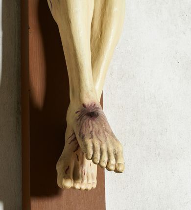 Zdjęcie nr 6: Figura umarłego Chrystusa przybita trzema gwoździami do krzyża o prostym zakończeniu ramion. Ciało w dużym zwisie, o ramionach przyjmujących kształt szerokiego „V”, na lekko ugiętych nogach, ze stopami skrzyżowanymi w układzie prawa na lewą, głowa opada na prawy bark. Twarz ma szczupłą, o dużych, zamkniętych oczach, wąskim nosie i ustach, okoloną krótką brodą i brązowymi włosami, sięgającymi ramion. Na głowie ma koronę cierniową. Ciało ma szczupłe i umięśnione, zwłaszcza w partii ramion i nóg, klatka piersiowa o delikatnie podkreślonej muskulaturze. W prawym boku rana z rzeźbionymi kroplami krwi. Białe, krótkie perizonium zawieszone na podwójnym sznurze, odsłaniające prawe udo, ze zwisem tkaniny przy prawym boku i w partii podbrzusza. Polichromia ciała naturalistyczna z zaznaczonymi śladami męki.  Na zakończeniu pionowej belki krzyża zwój z napisem „I. N. / R. I.”