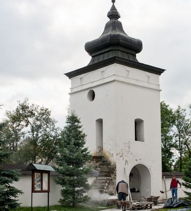 Zdjęcie nr 6: Kościół orientowany, murowany z kamienia, jednonawowy, z prostokątną, trójprzęsłową nawą oraz węższym dwuprzęsłowym prezbiterium zamkniętym trójbocznie, z niewielką prostokątną zakrystią przy północnej ścianie. Od zachodu wieża na planie kwadratu, do północnej ściany nawy dobudowana kaplica Matki Boskiej Karmelitańskiej, do południowej niewielka kruchta. Prezbiterium sklepione żebrowo z jednym rzeźbionym kroksztynem; żebra pokryte późniejszą dekoracją stiukową. Nawa wtórnie sklepiona kolebką z lunetami na gurtach, rozczłonkowana opilastrowanymi półfilarami. Pilastry i zacheuszki ozdobione stiukową ornamentacją. Do zakrystii prowadzi kamienny portal. Kościół opięty grubymi szkarpami jednouskokowymi, nakrytymi daszkami. W dwóch oknach prezbiterium i jednym nawy od południa kamienne maswerki; w zakrystii od wschodu wąskie okienko, tzw. romańskie. W pólnocno-wschodnim narożniku nawy wtórnie wkomponowany rzeźbiony, bardzo zniszczony kroksztyn. Z południowej kruchty do nawy prowadzi kamienny portal o trzech parach kolumienek dźwigających archiwolty. Nawa i prezbiterium nakryte dachem, na ich styku wieżyczka na sygnaturkę. Wieża smukła, bez podziałów architektonicznych, ściany najwyższej kondygnacji cofnięte w głąb, przy krawędzi kamienne kroksztyny, pozostałe po niezachowanej drewnianej hurdycji. Wieża zwieńczona ceglaną attyką, zasłaniającą dwuspadowy dach. W górnej części jej trzonu okna usytuowane z czterech stron. W miejscu hurdycji, na zachodniej ścianie zegar. 

Kościół otoczony niskim murem kamiennym; od zachodu dzwonnica bramna na planie kwadratu z niesklepioną sienią przejściową, nakryta blaszanym hełmem; od południa i od wschodu bramki nakryte hełmami, przy czym jeden pokryty jest gontem, drugi blachą.